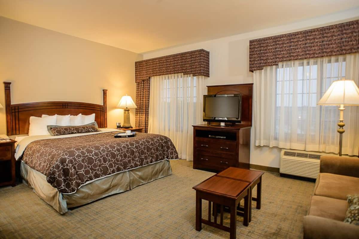 Una habitación de hotel con una cama grande, televisión, escritorio y sofá.