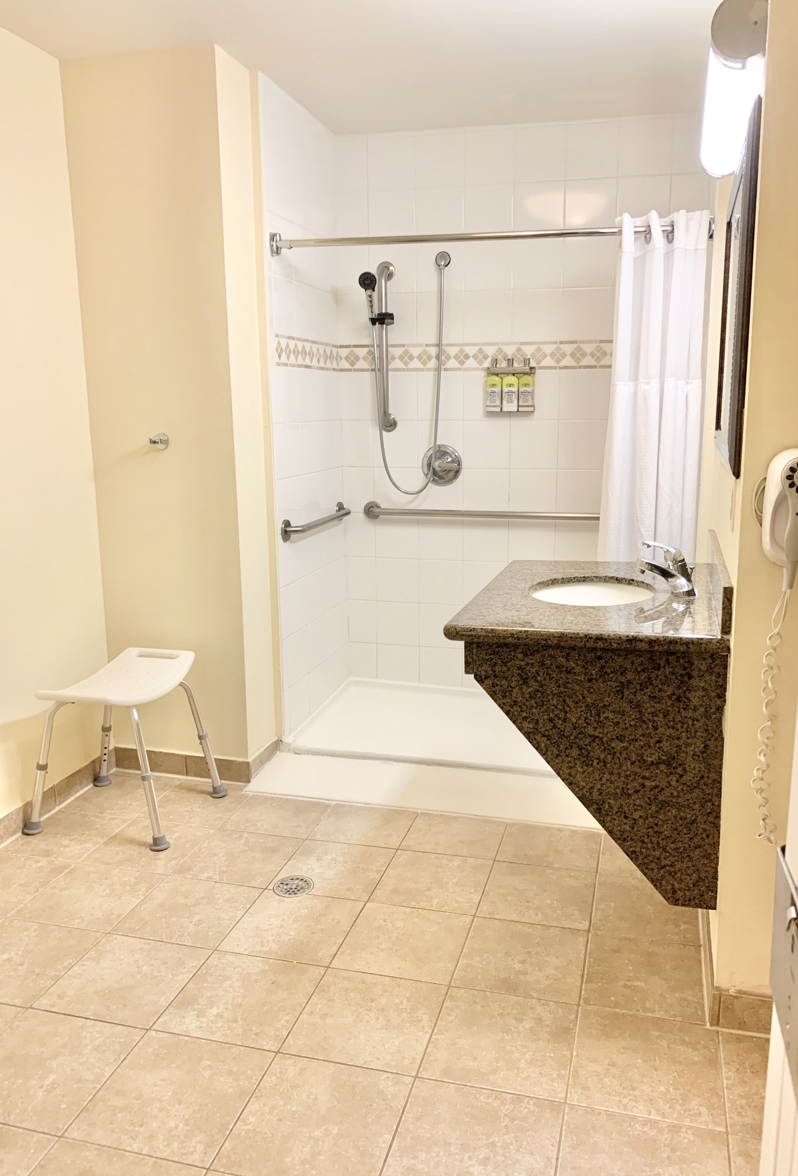 Une salle de bain avec une douche, un lavabo et un petit tabouret.