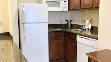 A kitchen with wooden cabinets, a white refrigerator, a microwave, a stove, and a dishwasher.