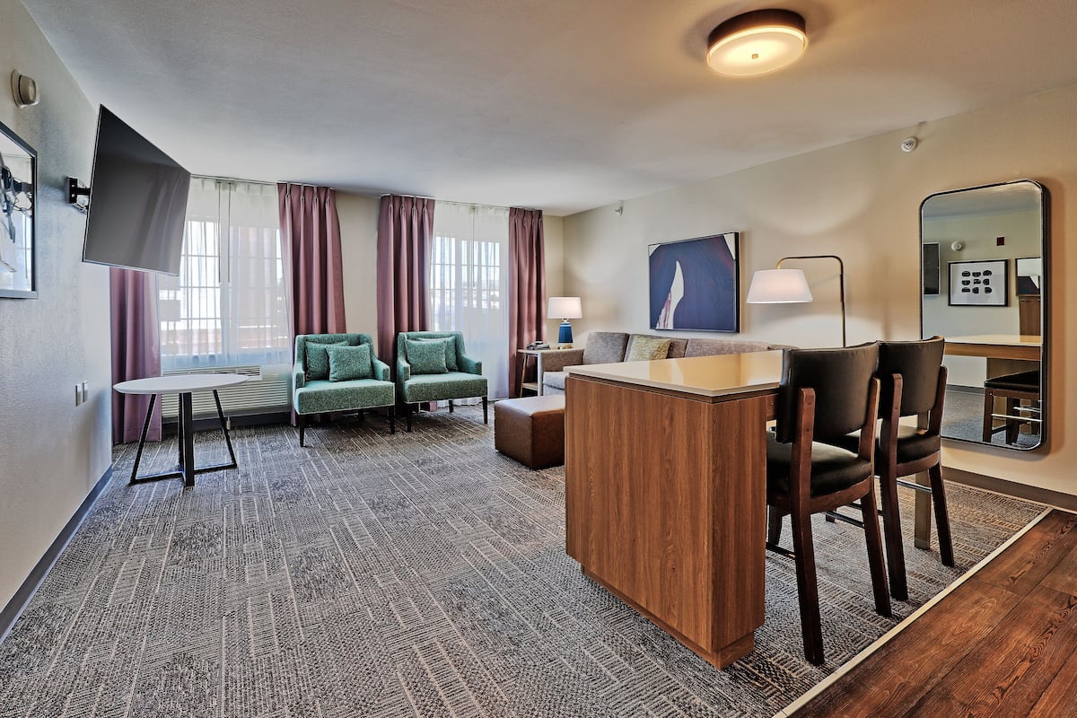 Une chambre d’hôtel avec un canapé, une petite table, un bureau en bois et un miroir.