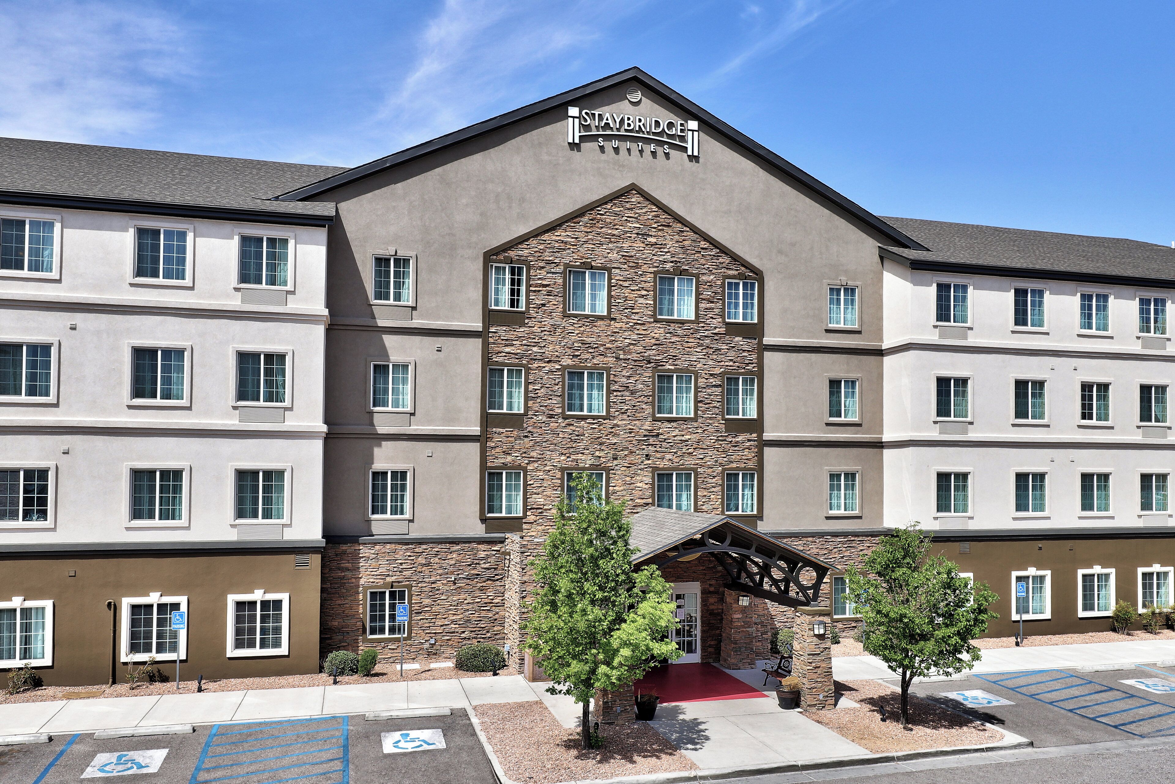 A multi-story hotel with a stone facade, multiple windows, and a red carpet entrance.
