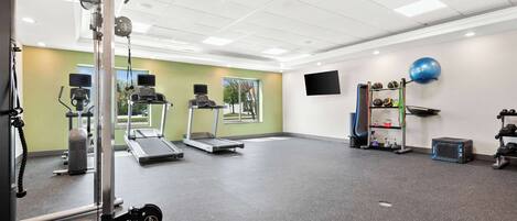 A gym with treadmills, weight machines, and exercise balls.