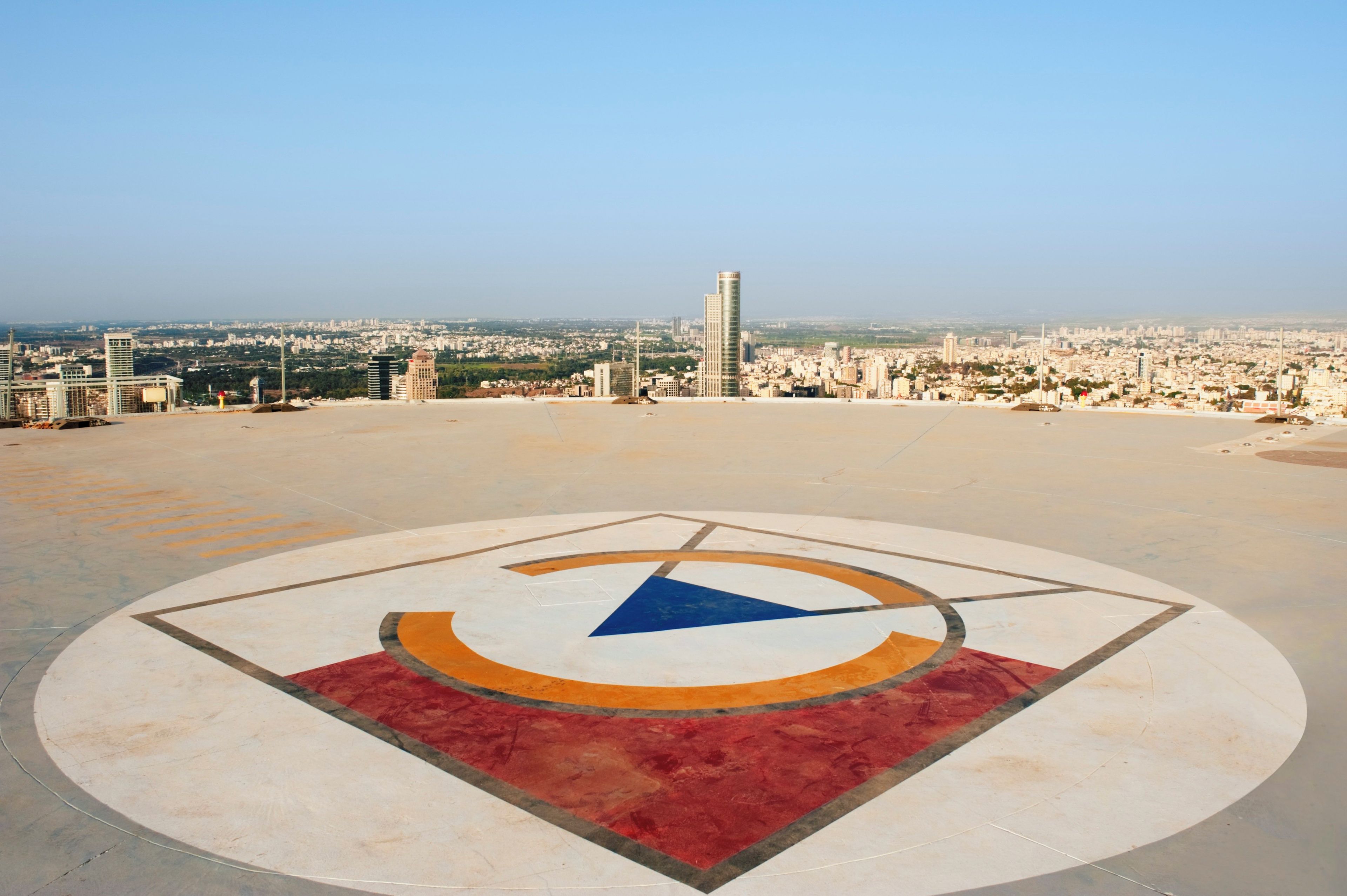 A circular plaza with a central emblem, surrounded by a cityscape with various buildings.