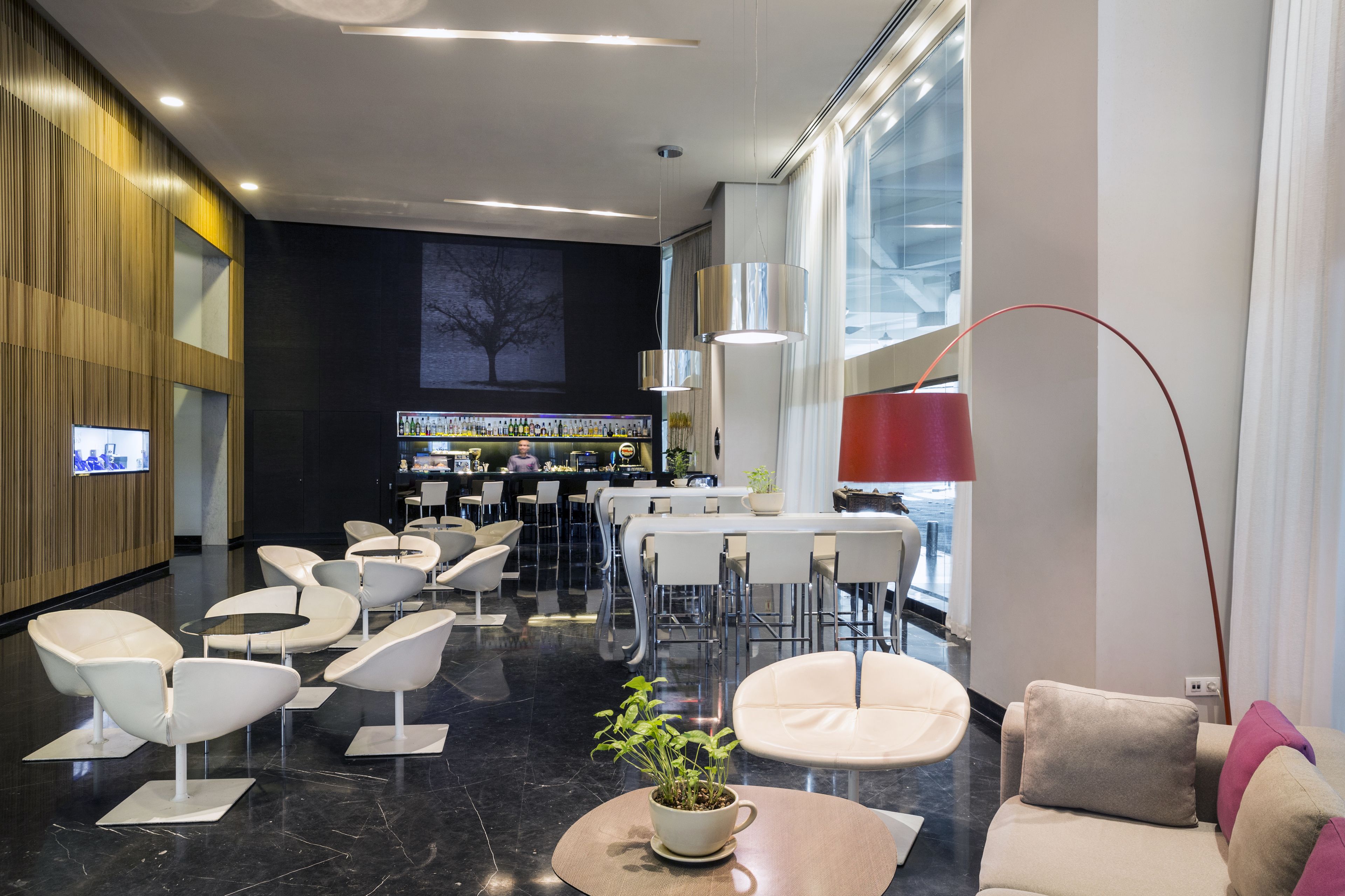 Un hall d’entrée moderne doté d’un bar, d’espaces aménagés pour s’asseoir et d’une grande fenêtre laissant entrer la lumière naturelle.