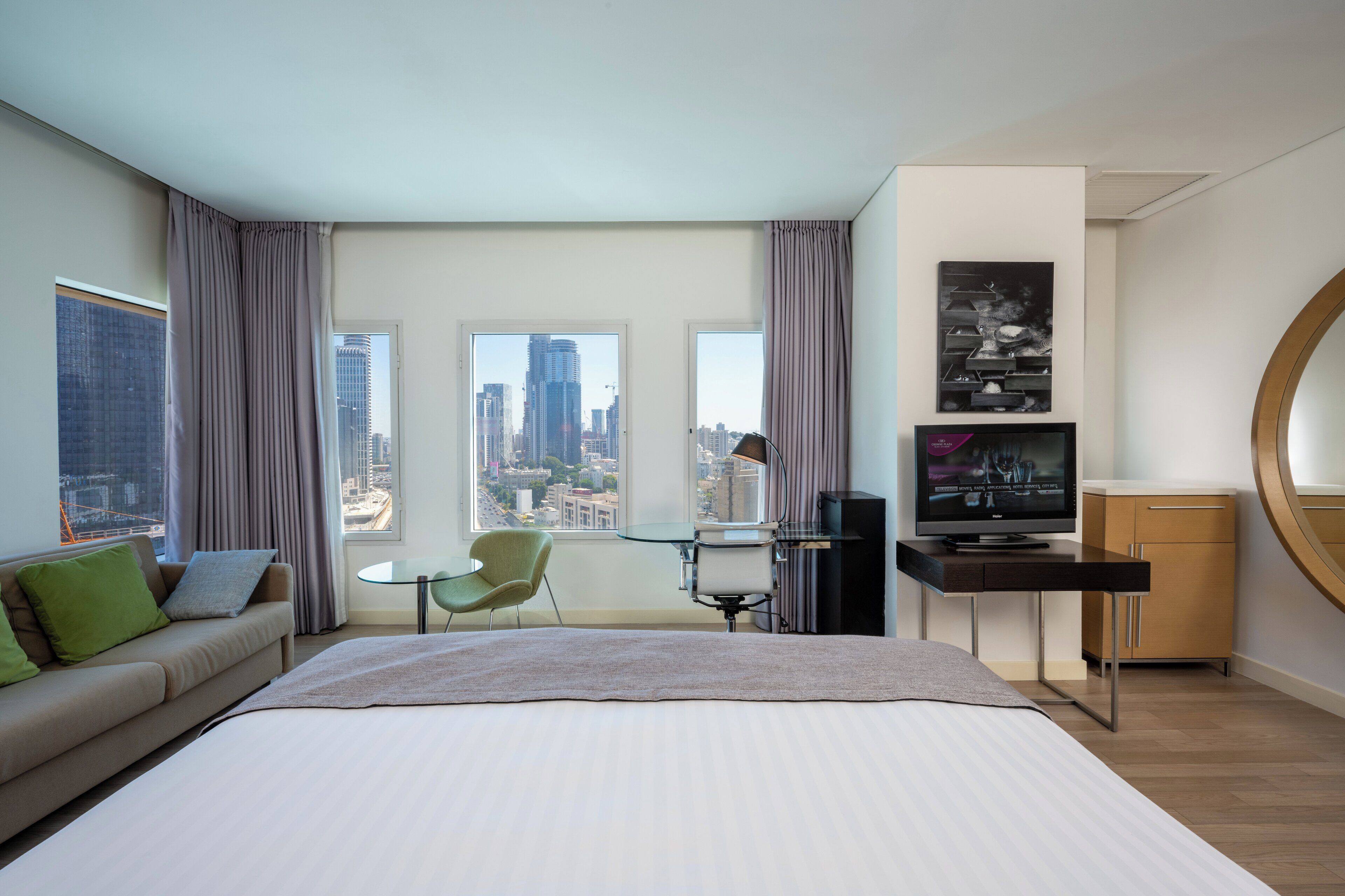 A modern hotel room with a large bed, a desk, a chair, and a television.