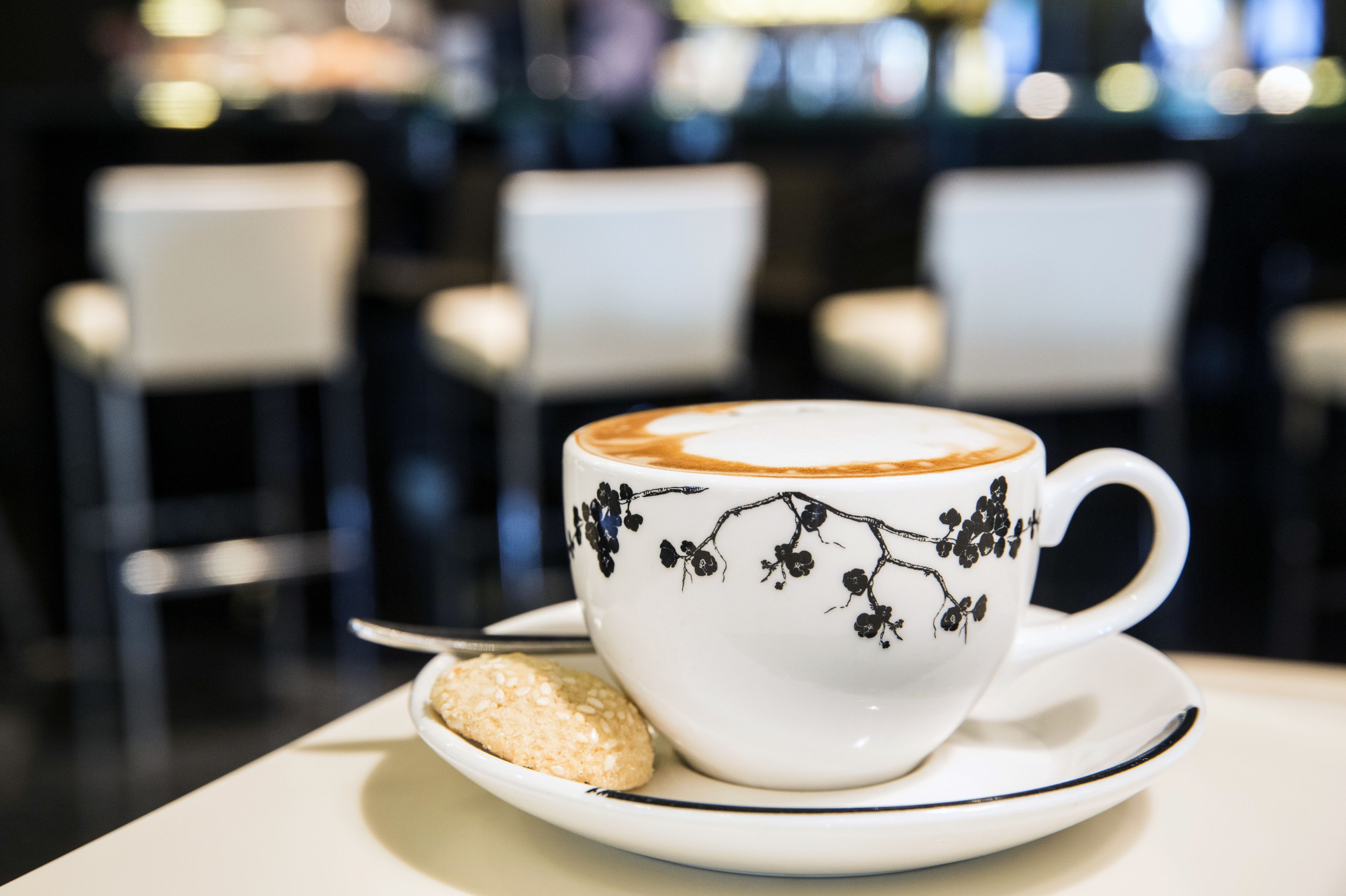 Una taza de café con diseño floral en la taza y el platillo, sobre una mesa.