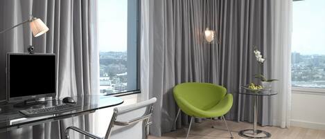 Un espacio de oficina moderno con un escritorio, computadora, silla y vista a la ciudad a través de amplias ventanas.