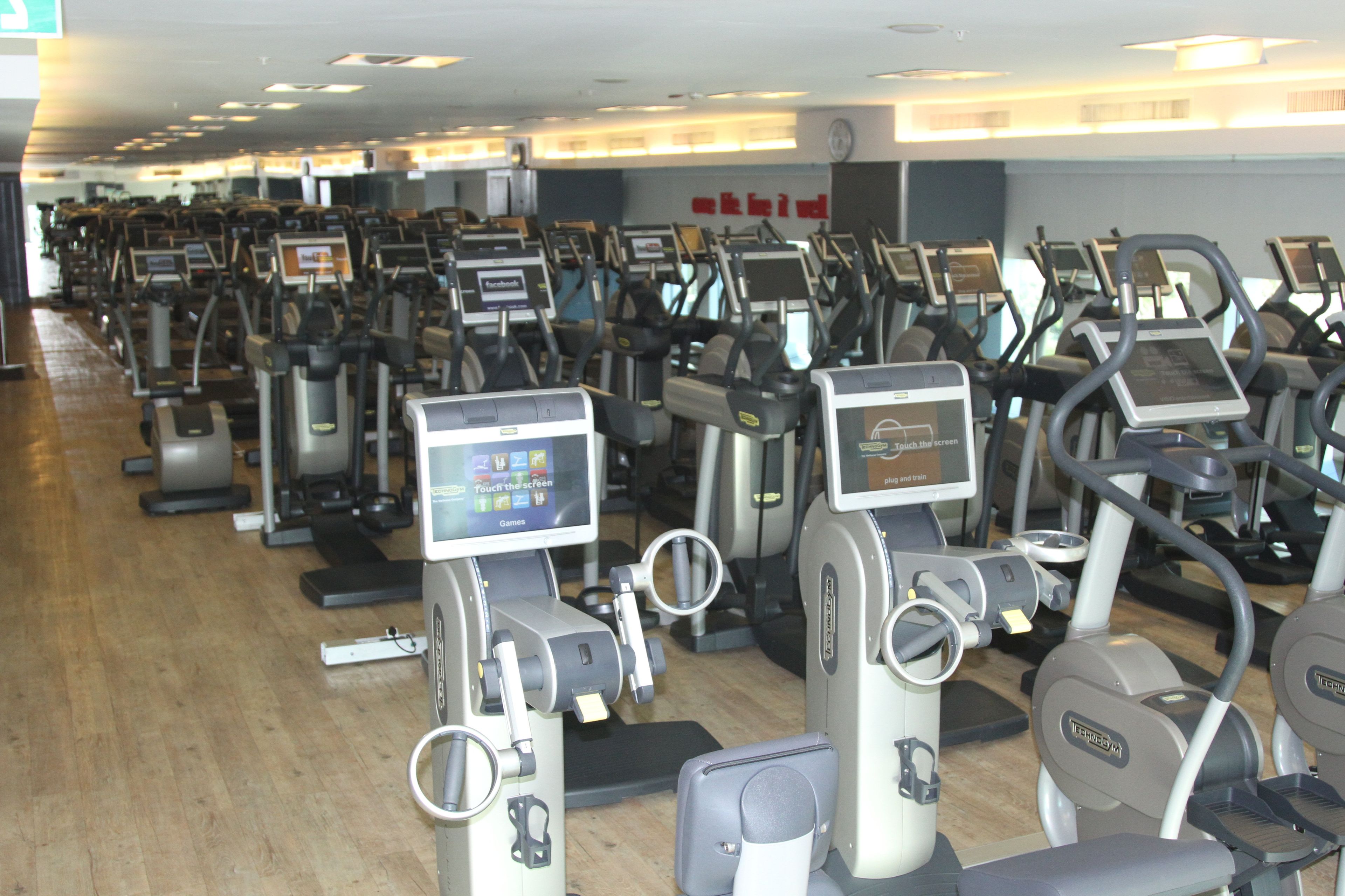 Varias bicicletas estáticas en un gimnasio, con pantallas digitales.