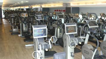 Varias bicicletas estáticas en un gimnasio, con pantallas digitales.
