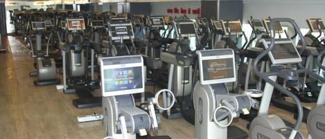 A row of stationary bikes in a gym with digital screens.