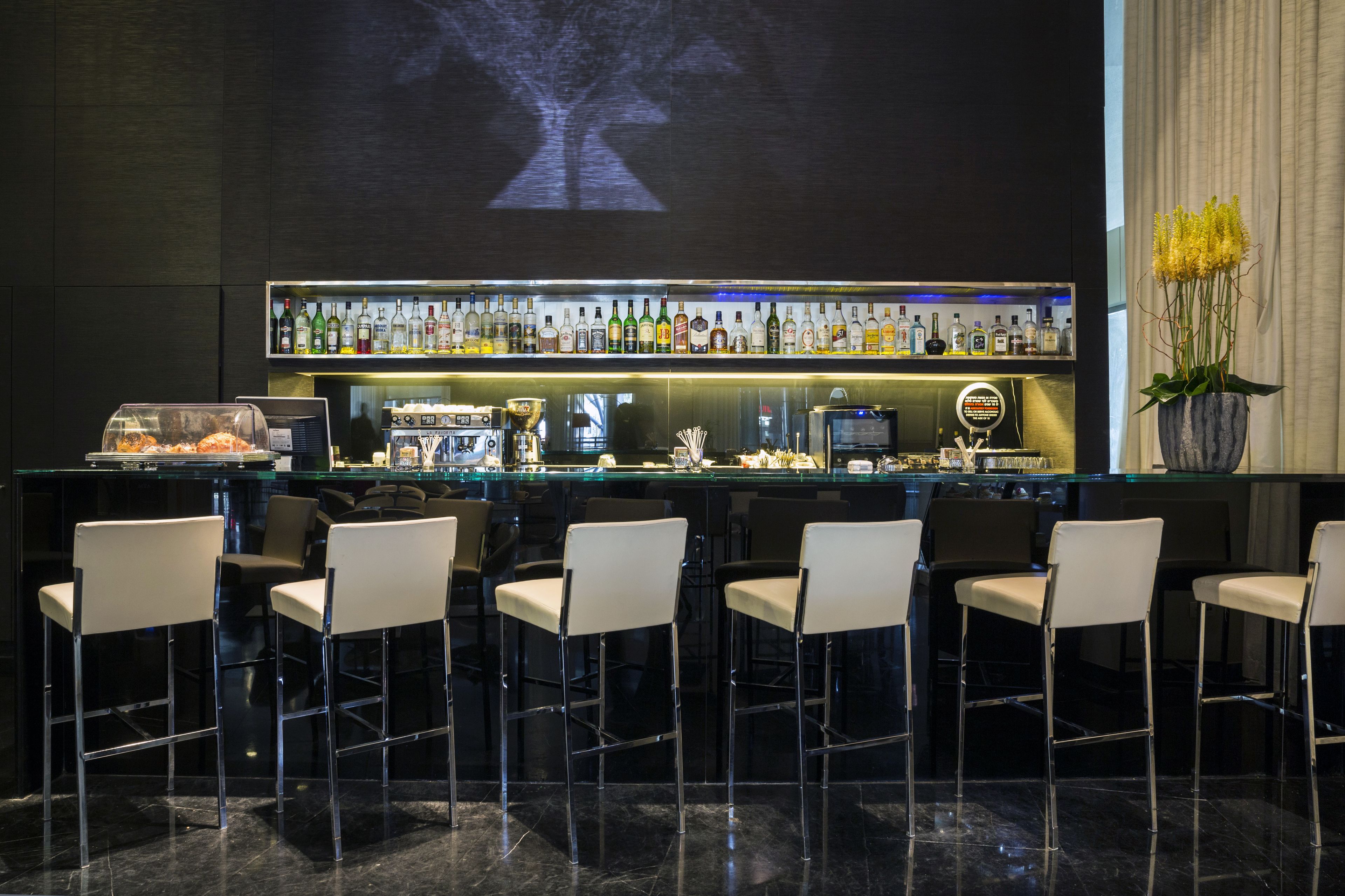 A bar area with a long counter, multiple chairs, and a projection screen displaying a tree.
