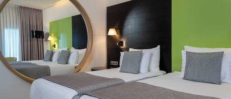 Habitación de hotel con dos camas, un espejo grande y una pared de acento verde.
