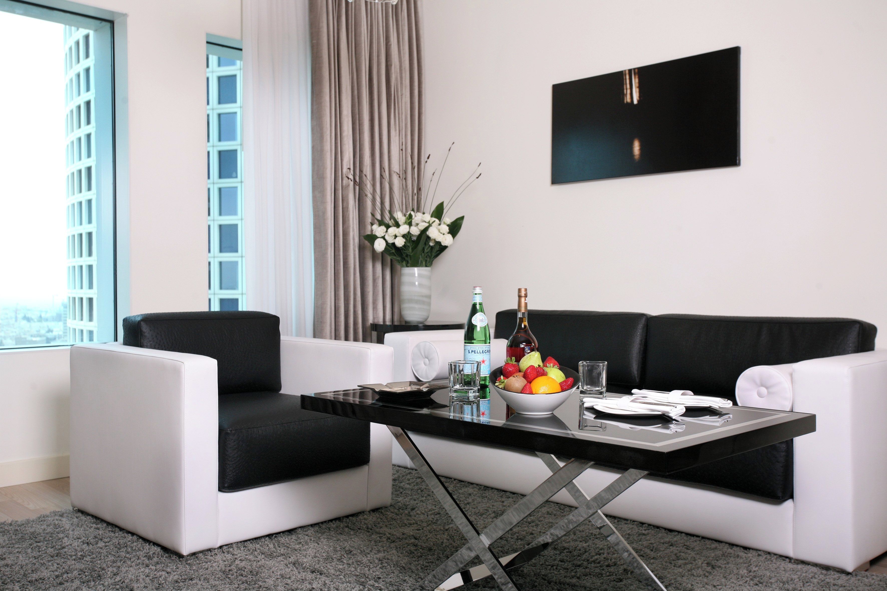A modern living room with a black and white sofa, a glass coffee table, and a fruit bowl.