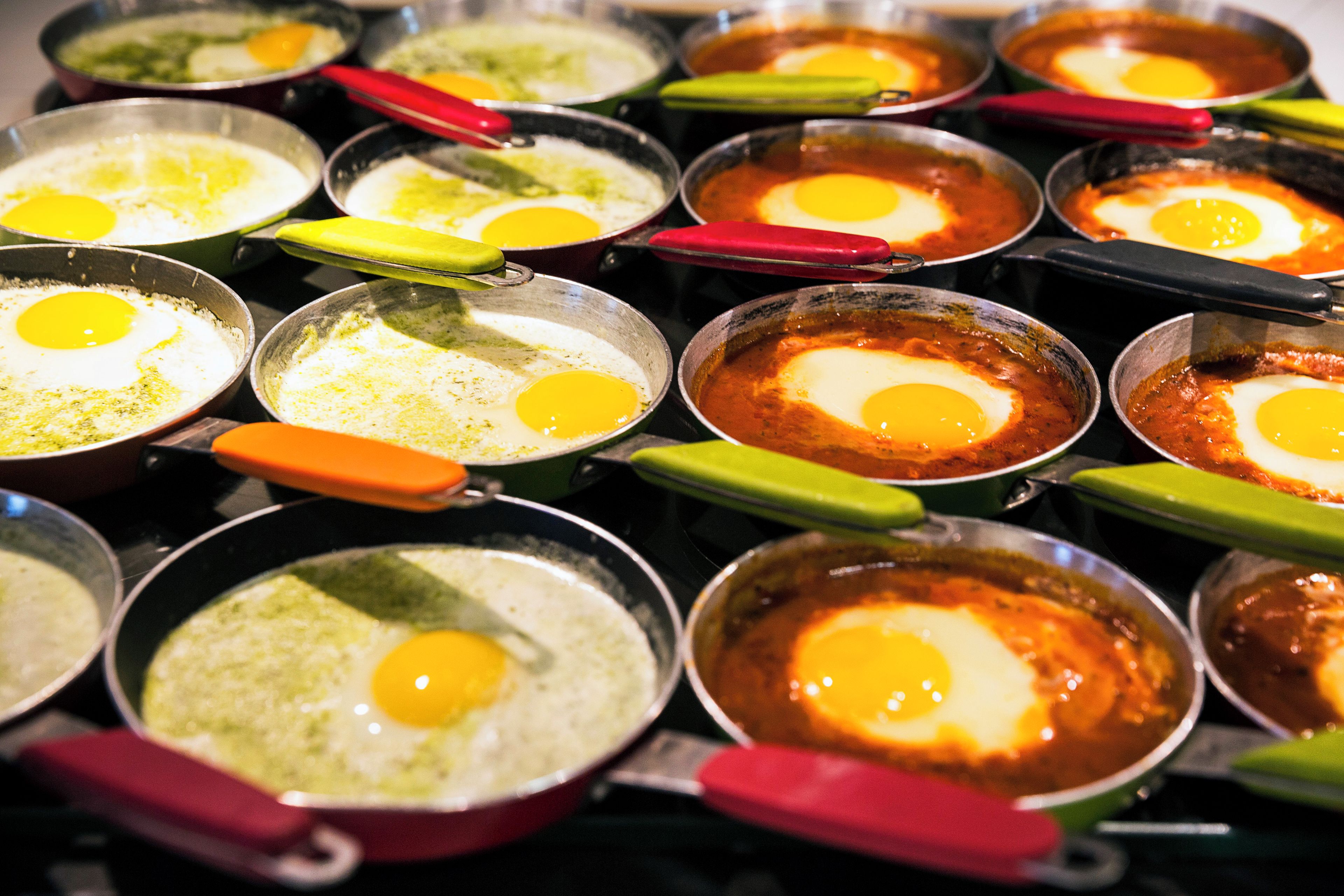Multiple cooking pans with eggs and sauces.