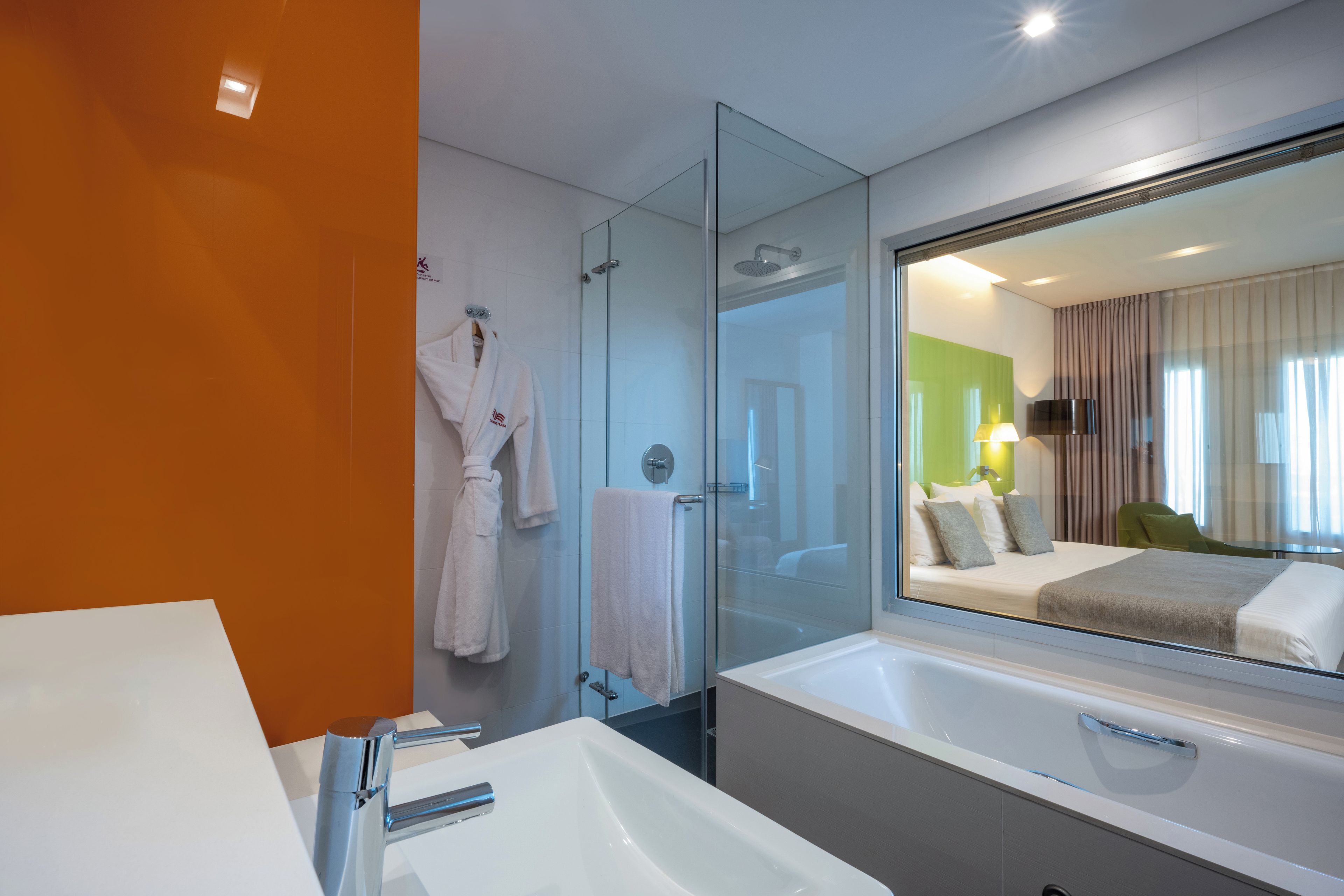 A modern bathroom with a glass-enclosed shower, a large mirror, and a white sink.