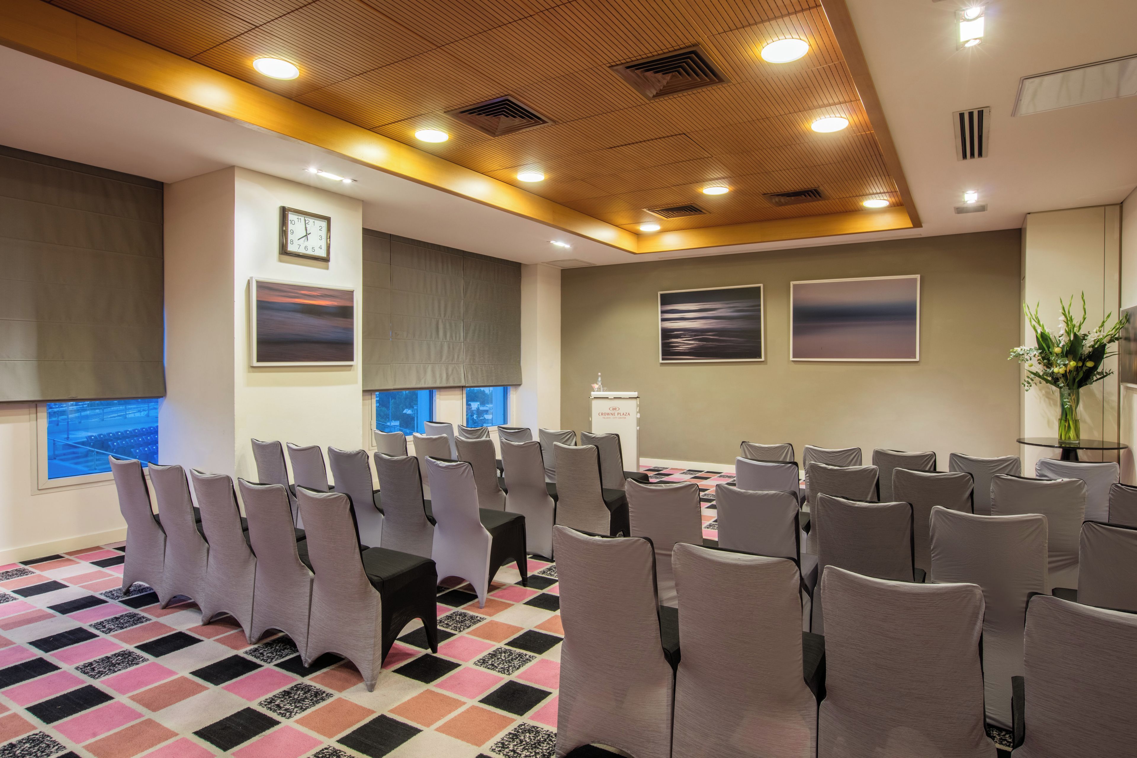 A conference room with rows of chairs, a clock, and framed artwork on the walls.