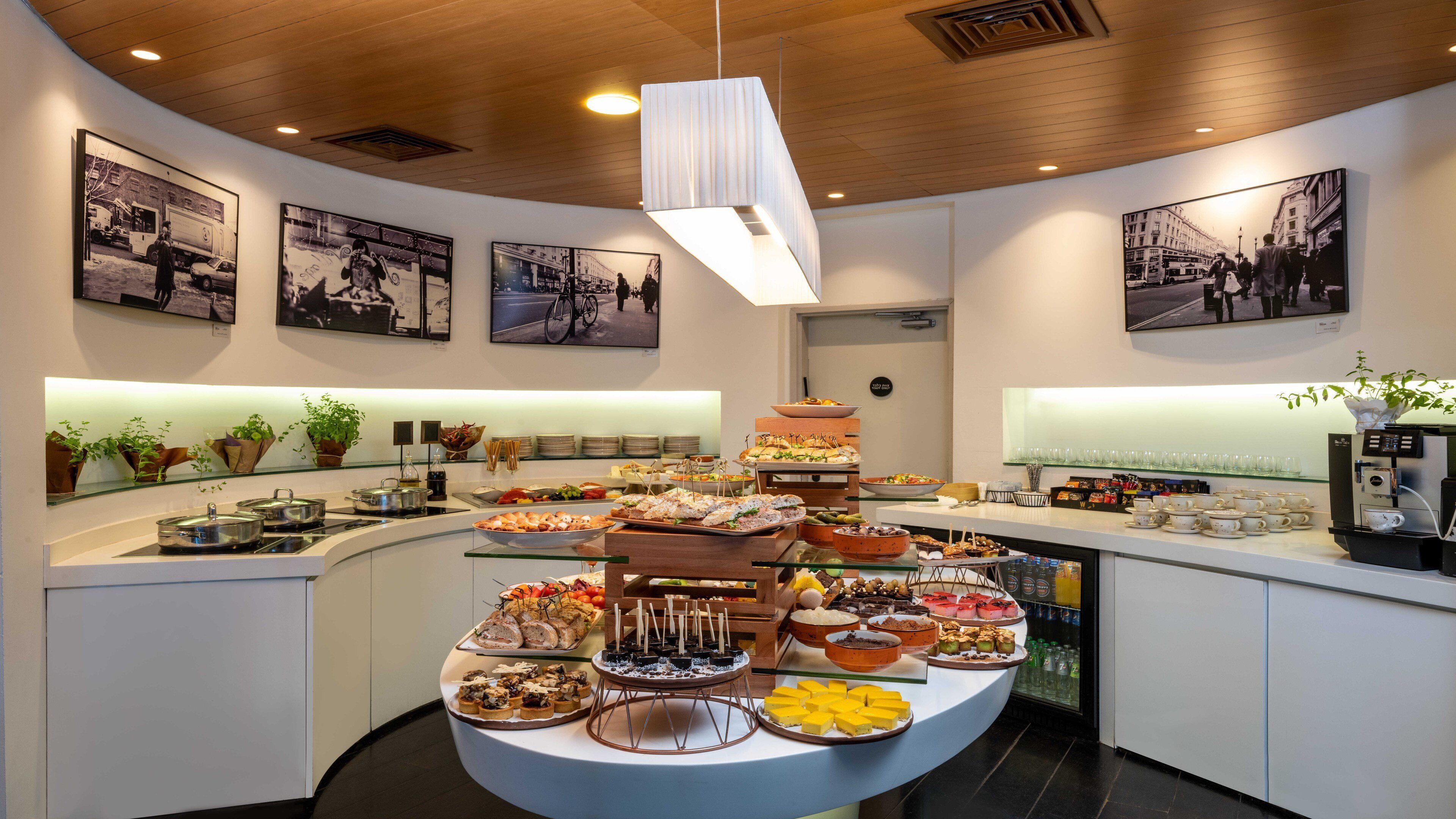 Un buffet proposant une variété de plats, une machine à café et des photographies encadrées accrochées aux murs.