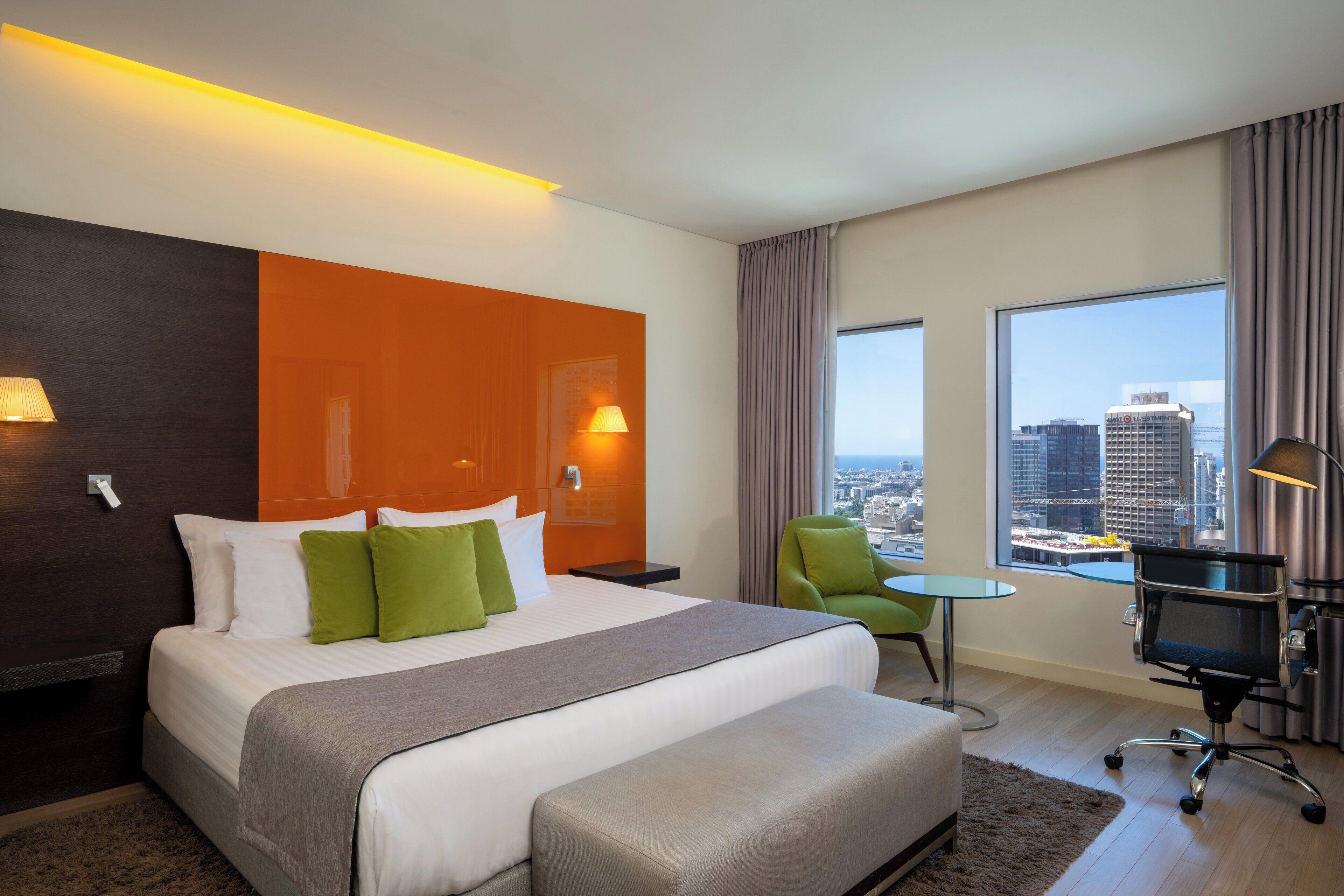 Habitación de hotel con una cama grande, un escritorio, una silla y vistas a la ciudad.