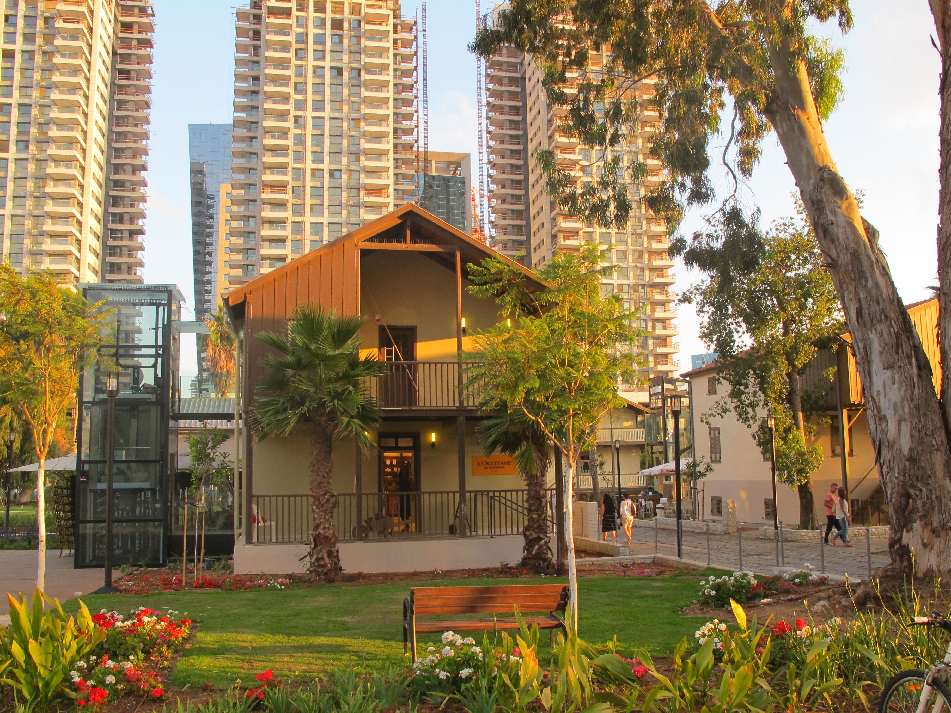 A building with a balcony, surrounded by greenery and a bench.
