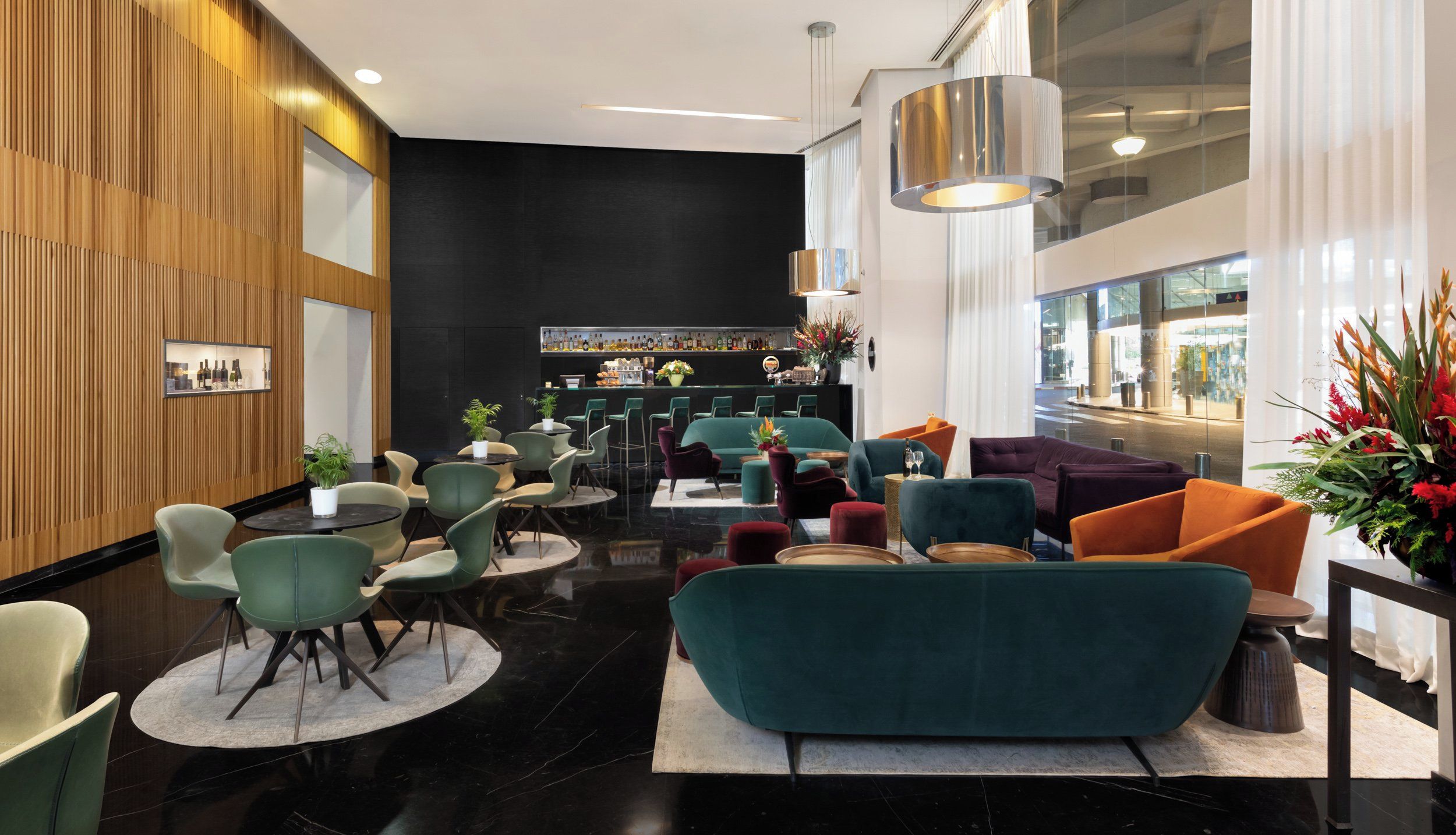 A modern lobby with a bar area, seating arrangements, and a large window providing a view of the outside.