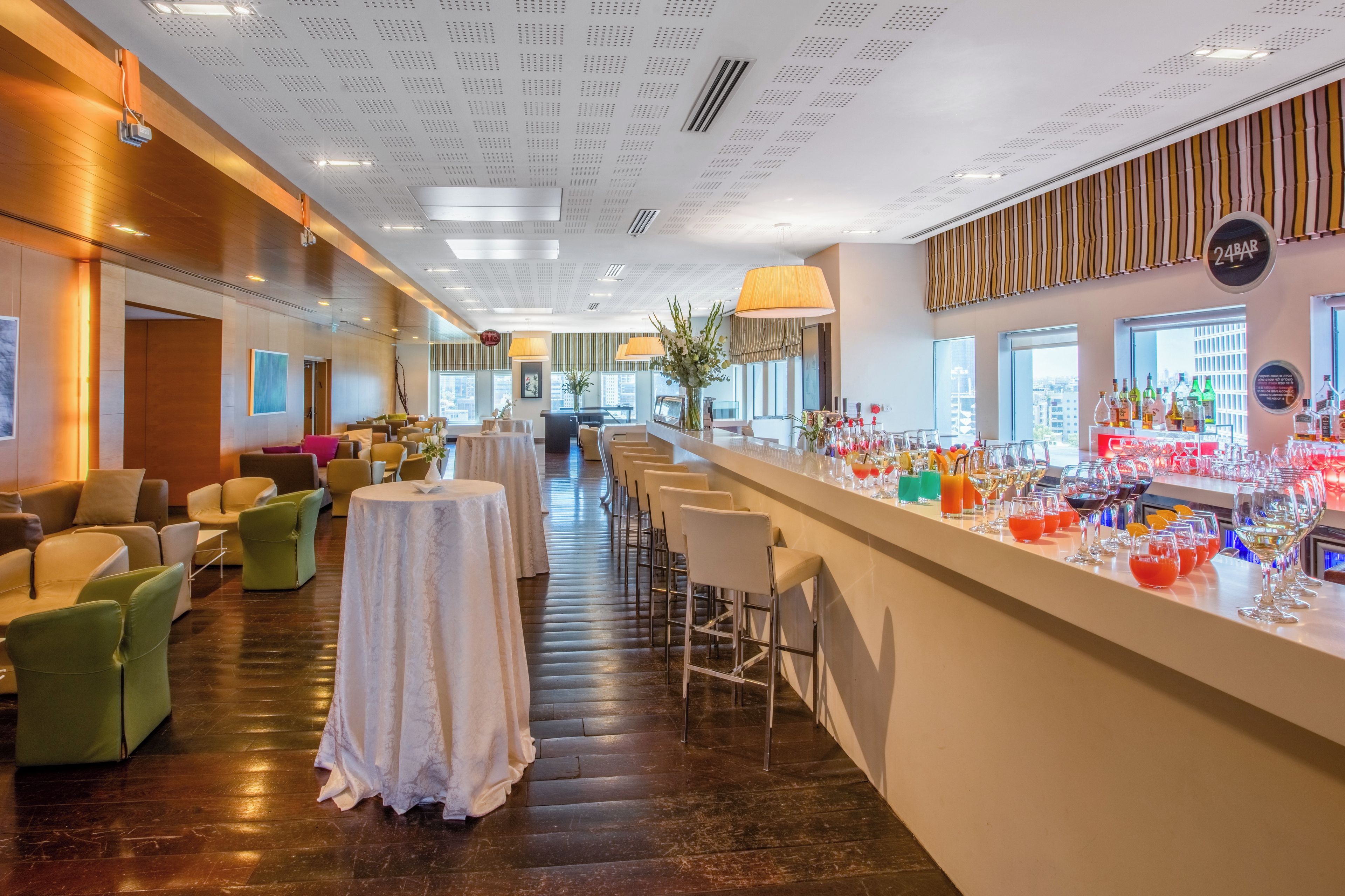 A hotel lobby with a bar area, seating arrangements, and a view of the city.