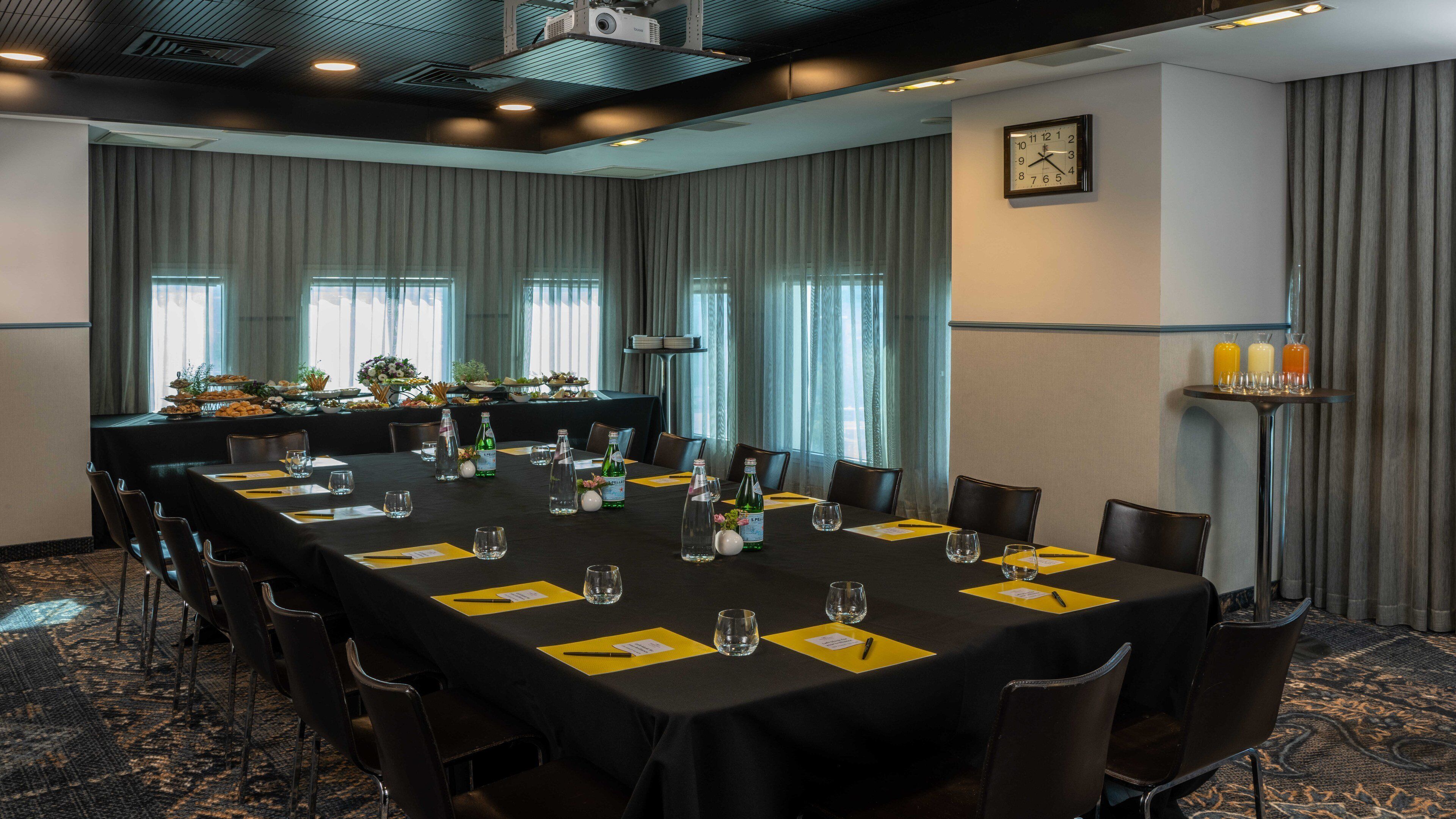 A conference room with a long table set for a meeting, equipped with chairs, water bottles, and name cards.