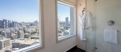 A modern bathroom with a city view, a glass shower enclosure, and a large window.