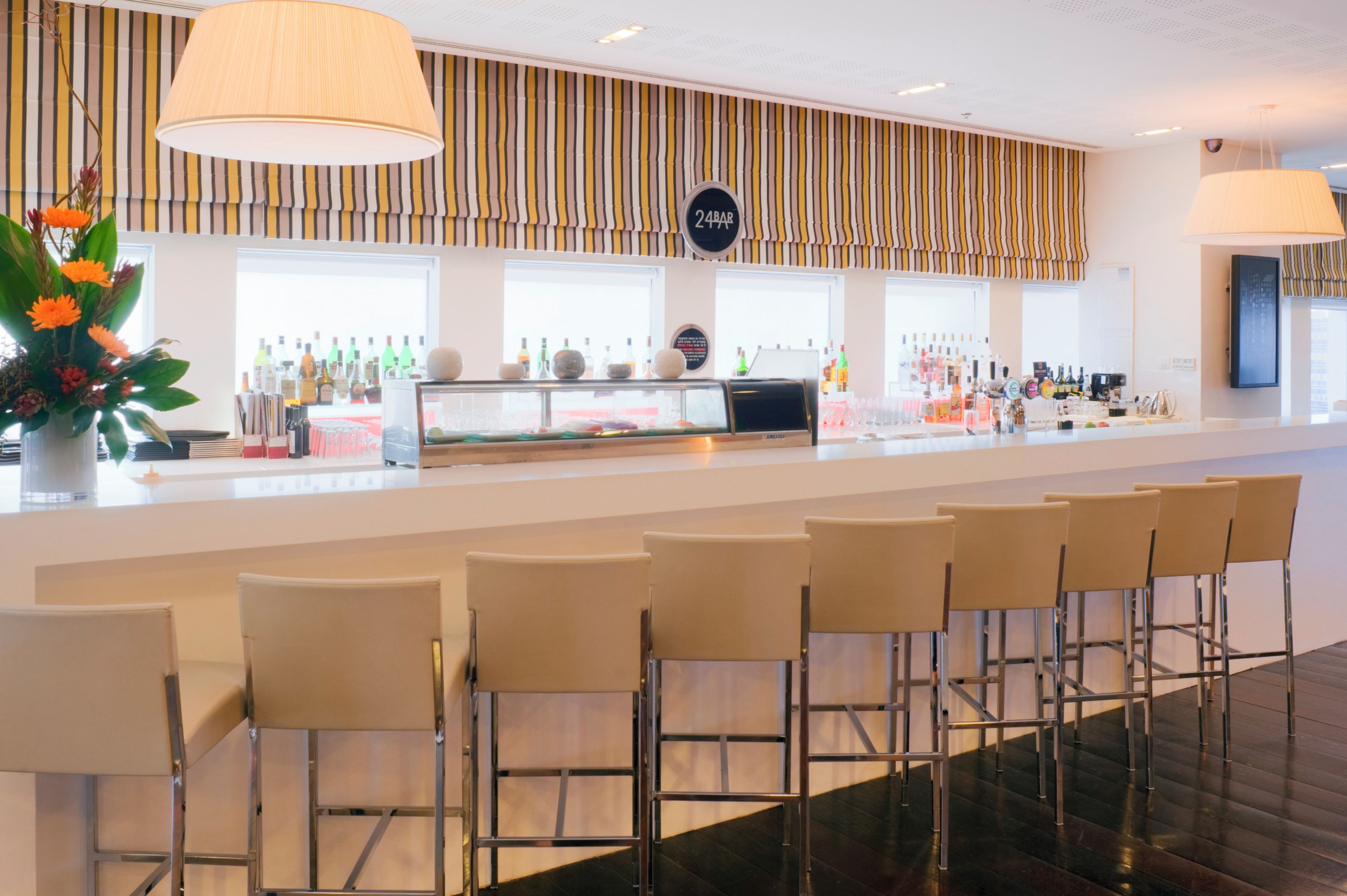 A bar area with a counter, bar stools, and a variety of bottles.