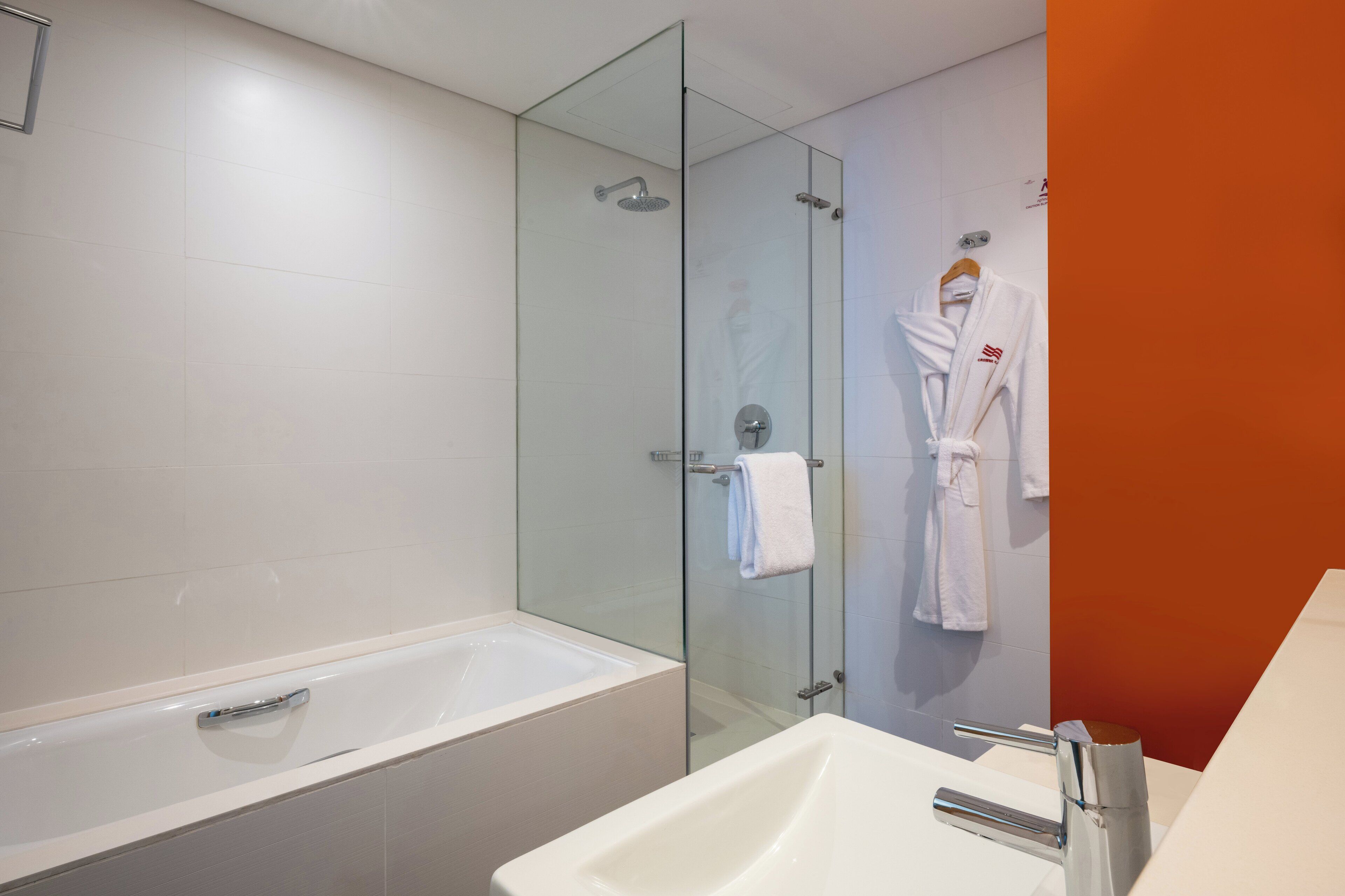Un baño moderno con ducha de vidrio, una bañera independiente y un lavamanos blanco.