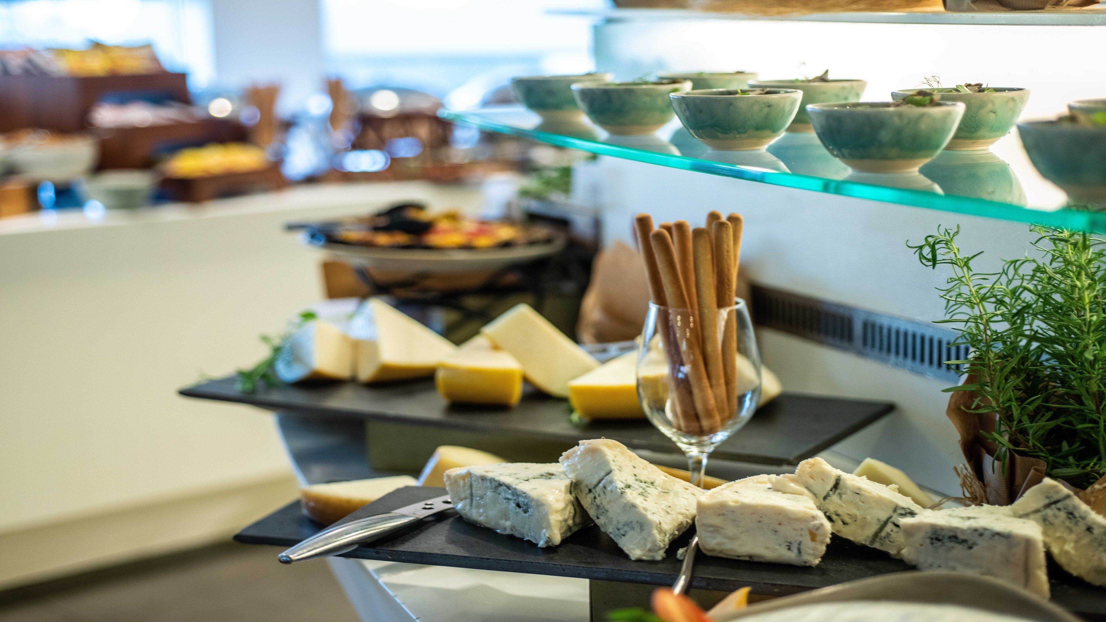 A buffet with various cheeses, breadsticks, and bowls on display.