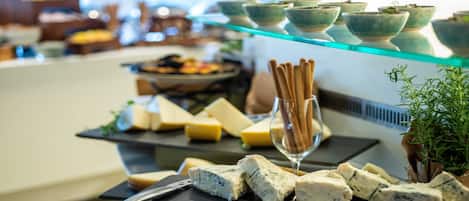 A buffet with various cheeses, breadsticks, and bowls on display.