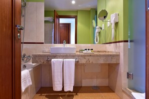Een badkamer met een wastafel, spiegel, handdoekhouder en douche.
