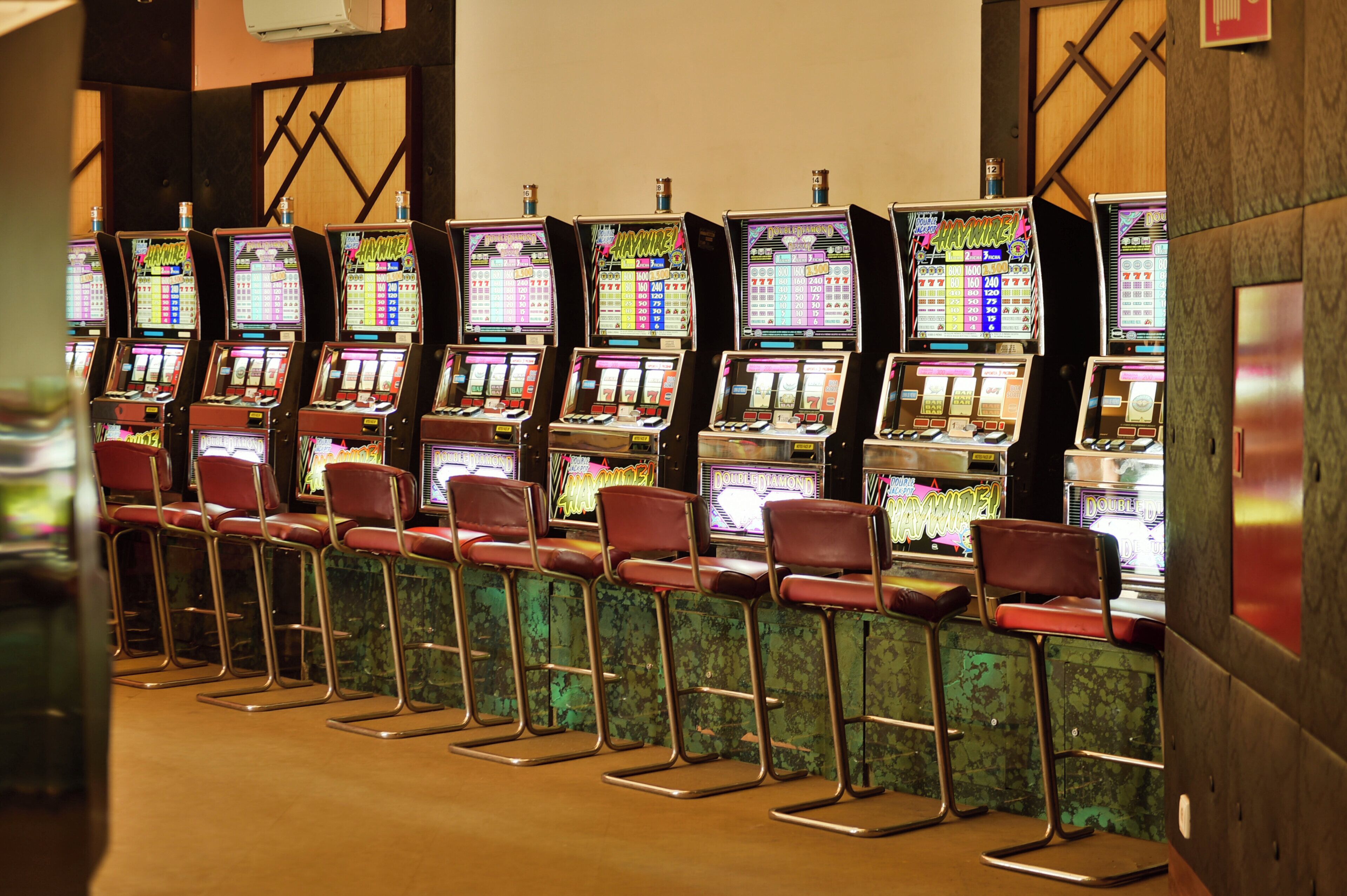 A row of slot machines with chairs in front.
