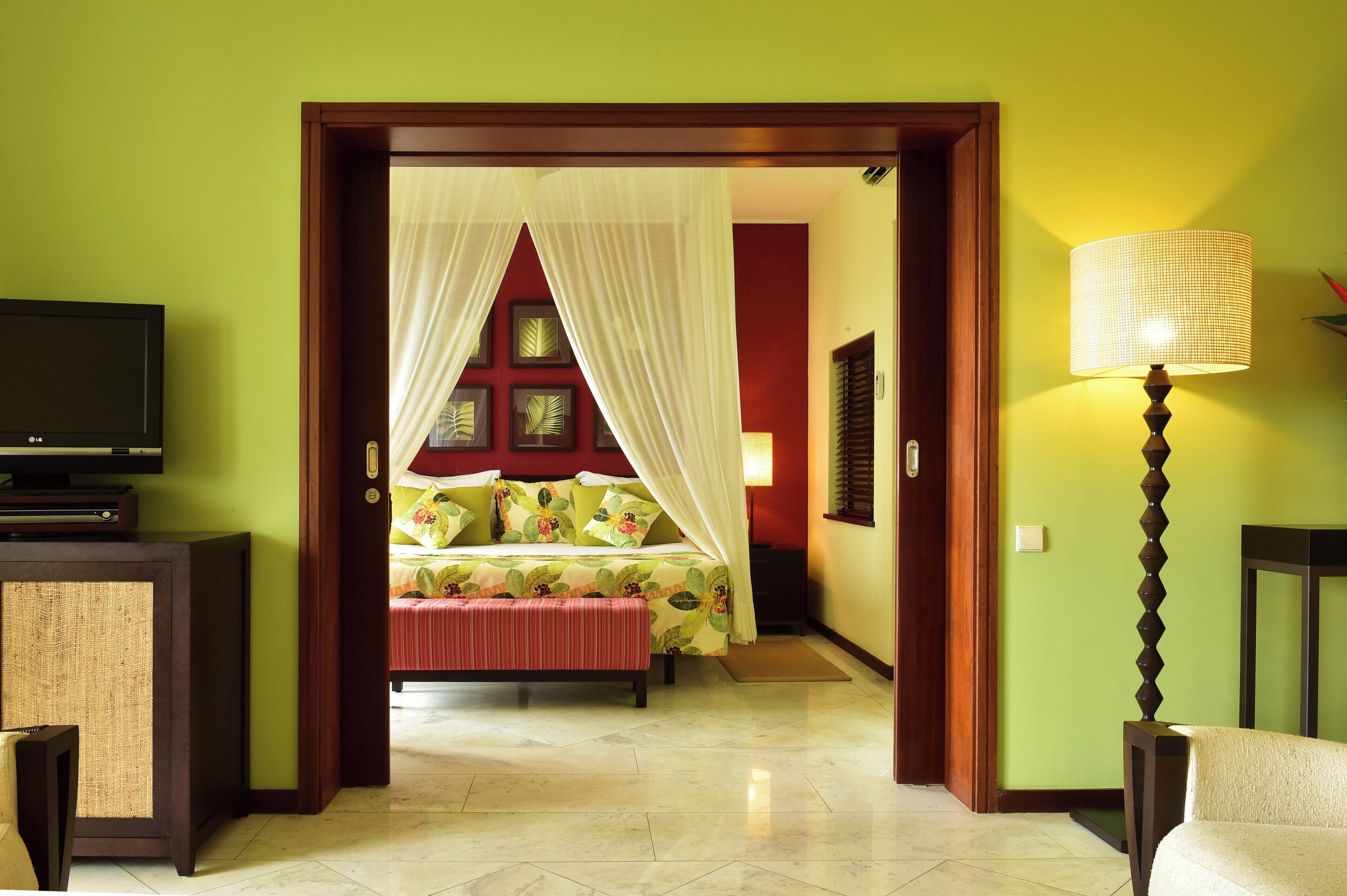 Quarto de hotel com cama, televisão e luminária.