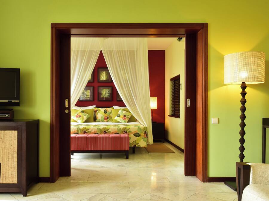 Quarto de hotel com cama, televisão e luminária.