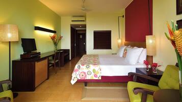Quarto de hotel com cama, escrivaninha, cadeira e televisão.