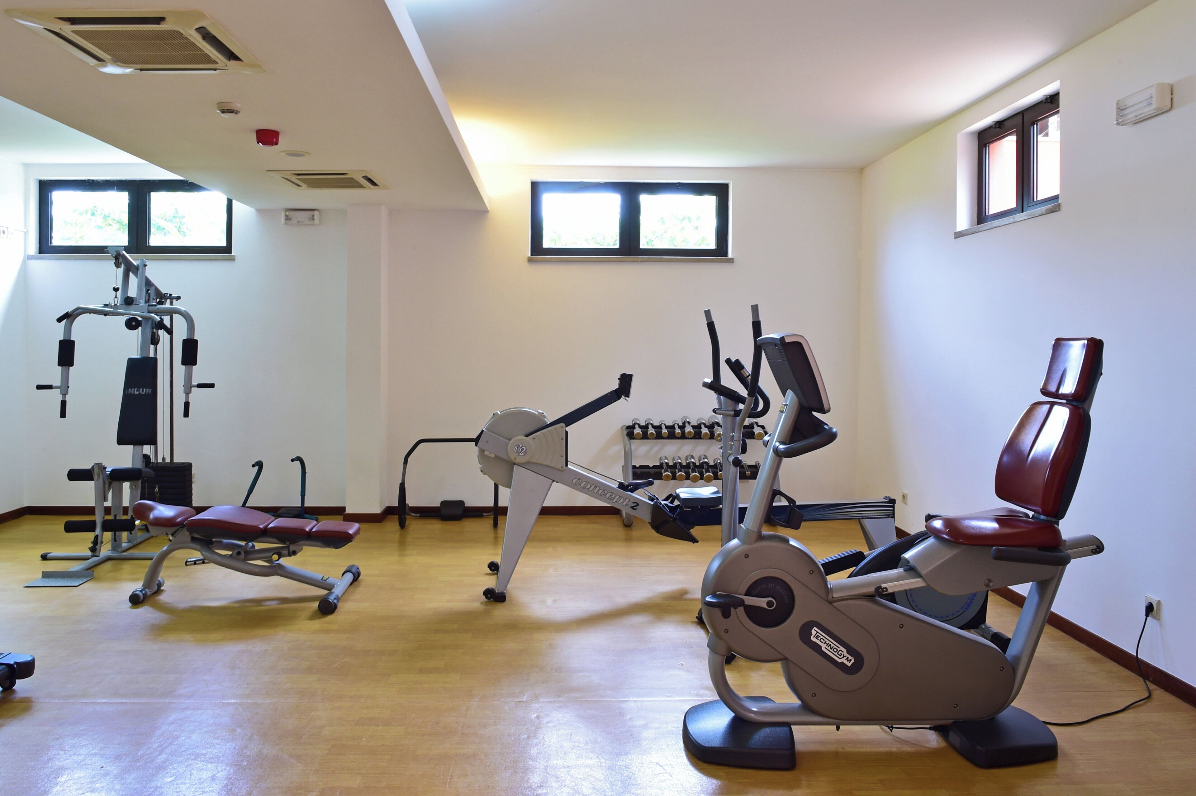 Una palestra con diverse attrezzature per esercizi, tra cui una cyclette ed attrezzi per pesi.