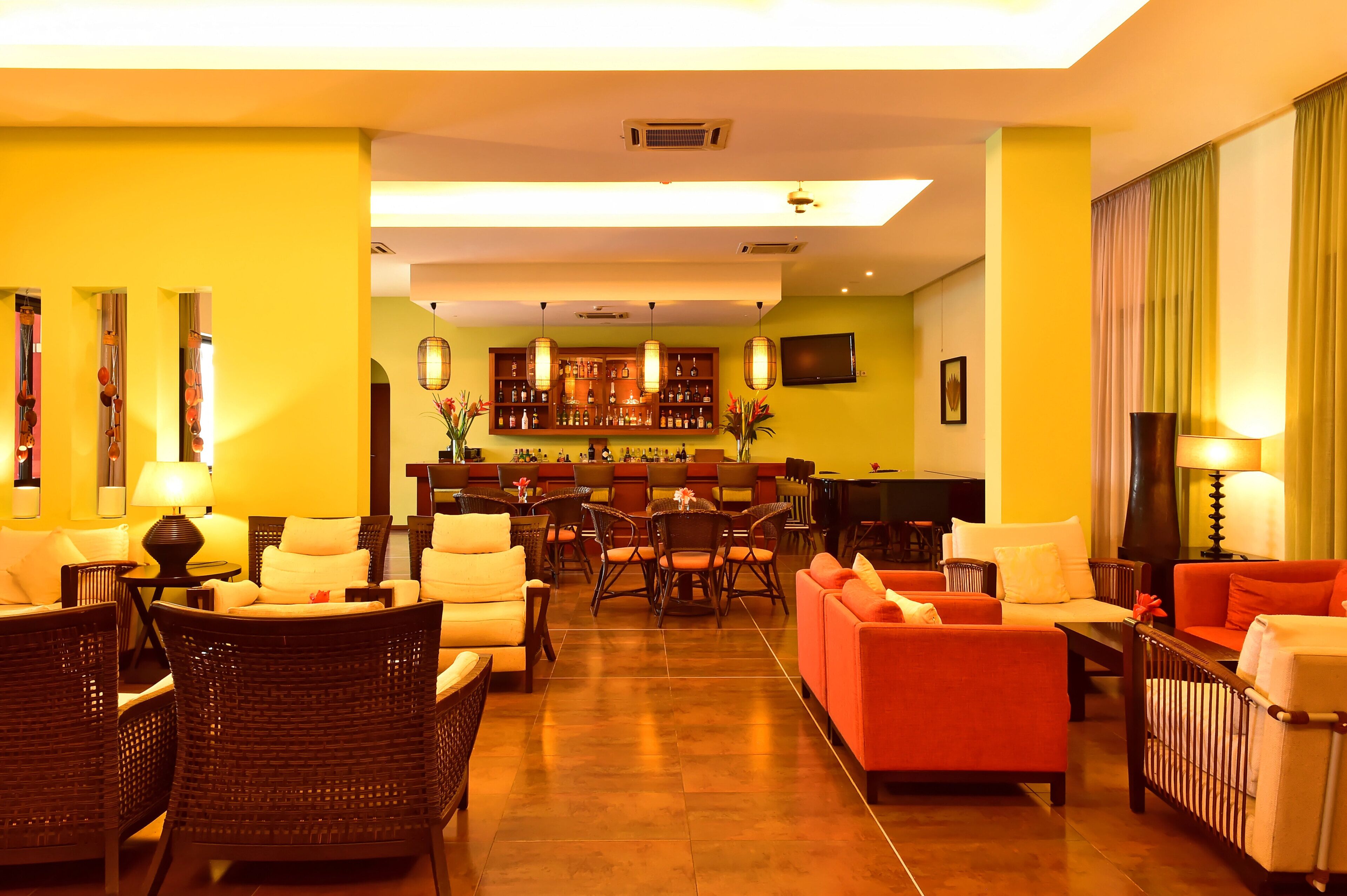 A hotel lobby with a bar area, seating arrangements, and a television.