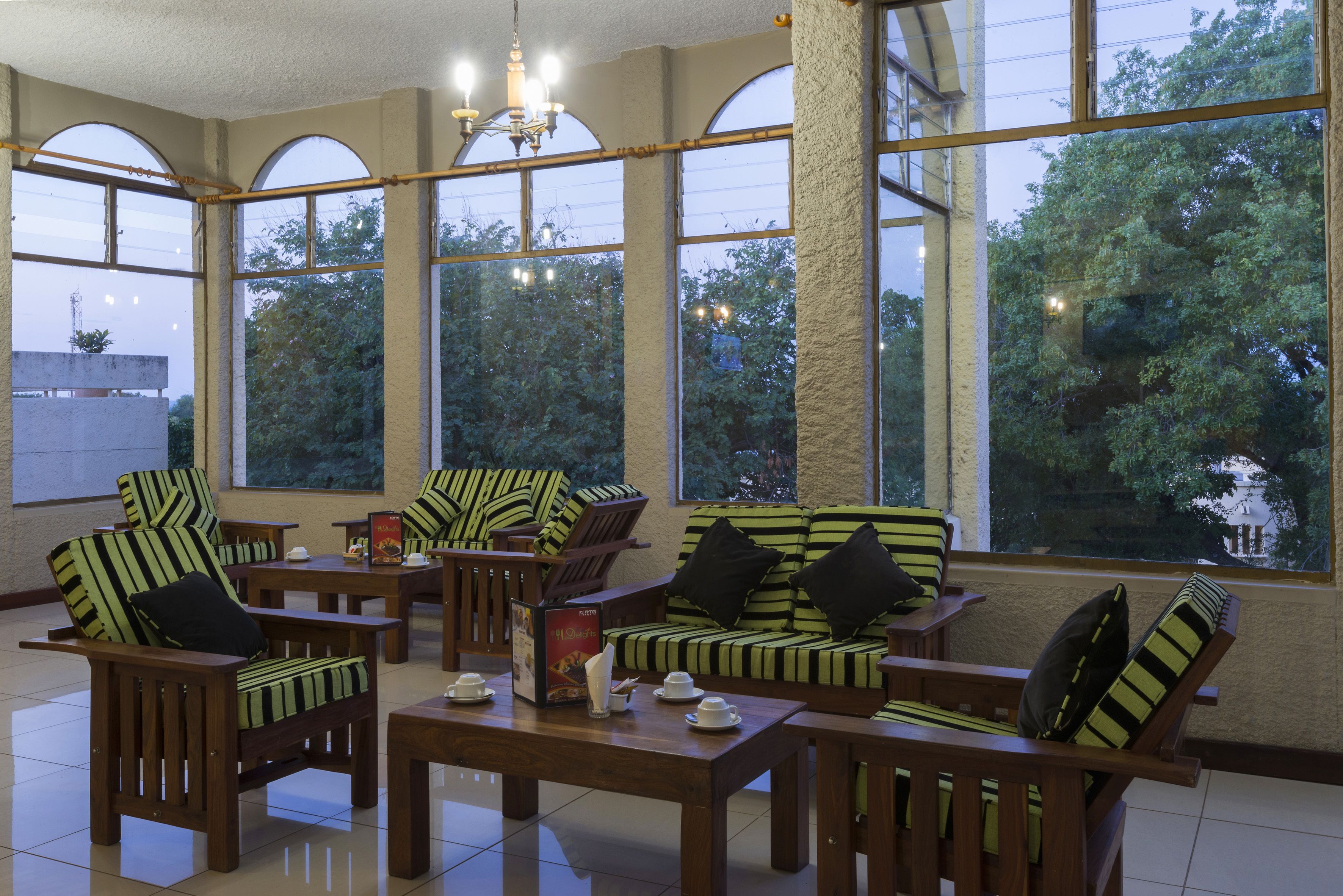 Una habitación luminosa con grandes ventanales, muebles de madera y un candelabro.