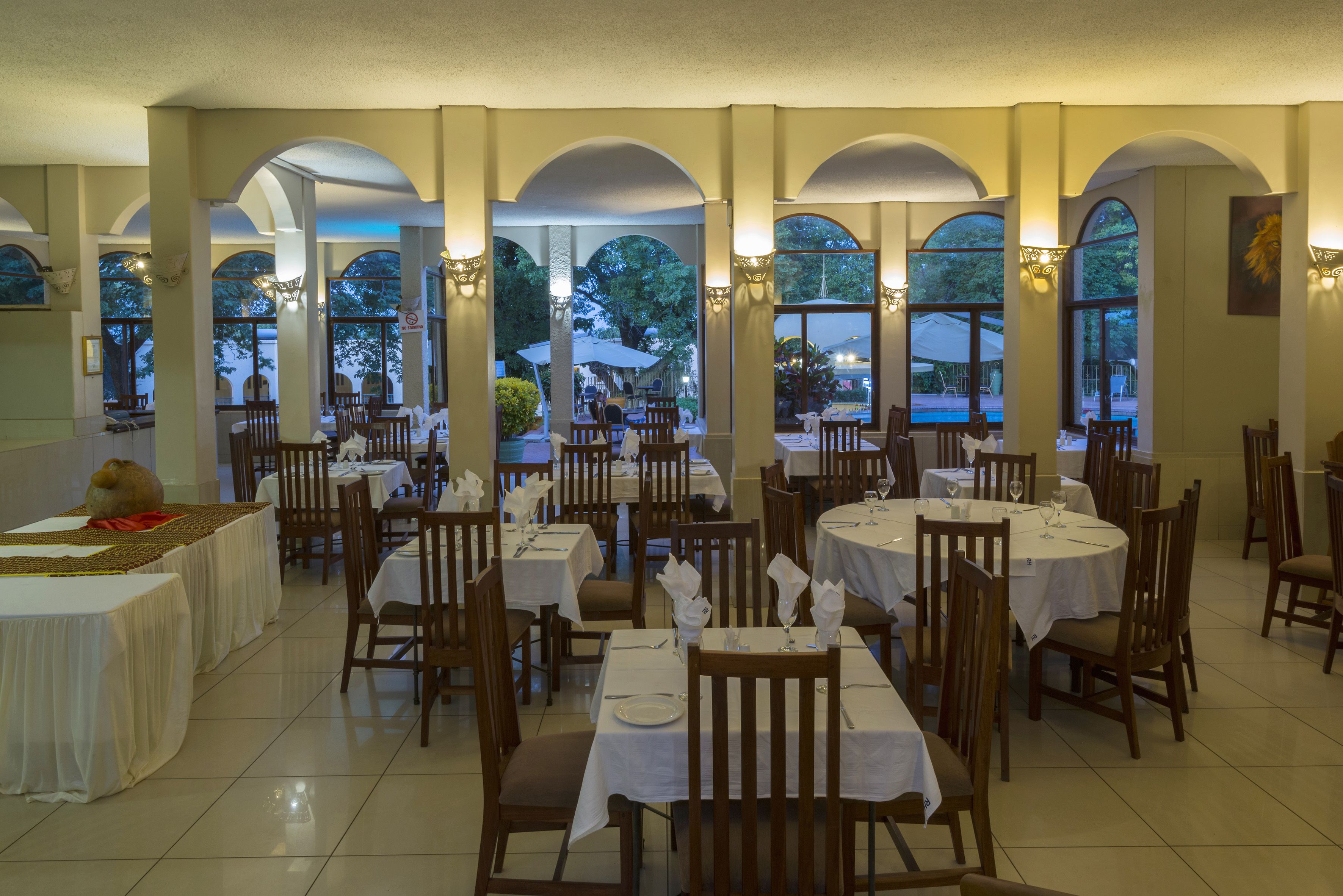 Un restaurant doté de nombreuses tables et chaises, de grandes fenêtres et offrant une vue sur l’extérieur.