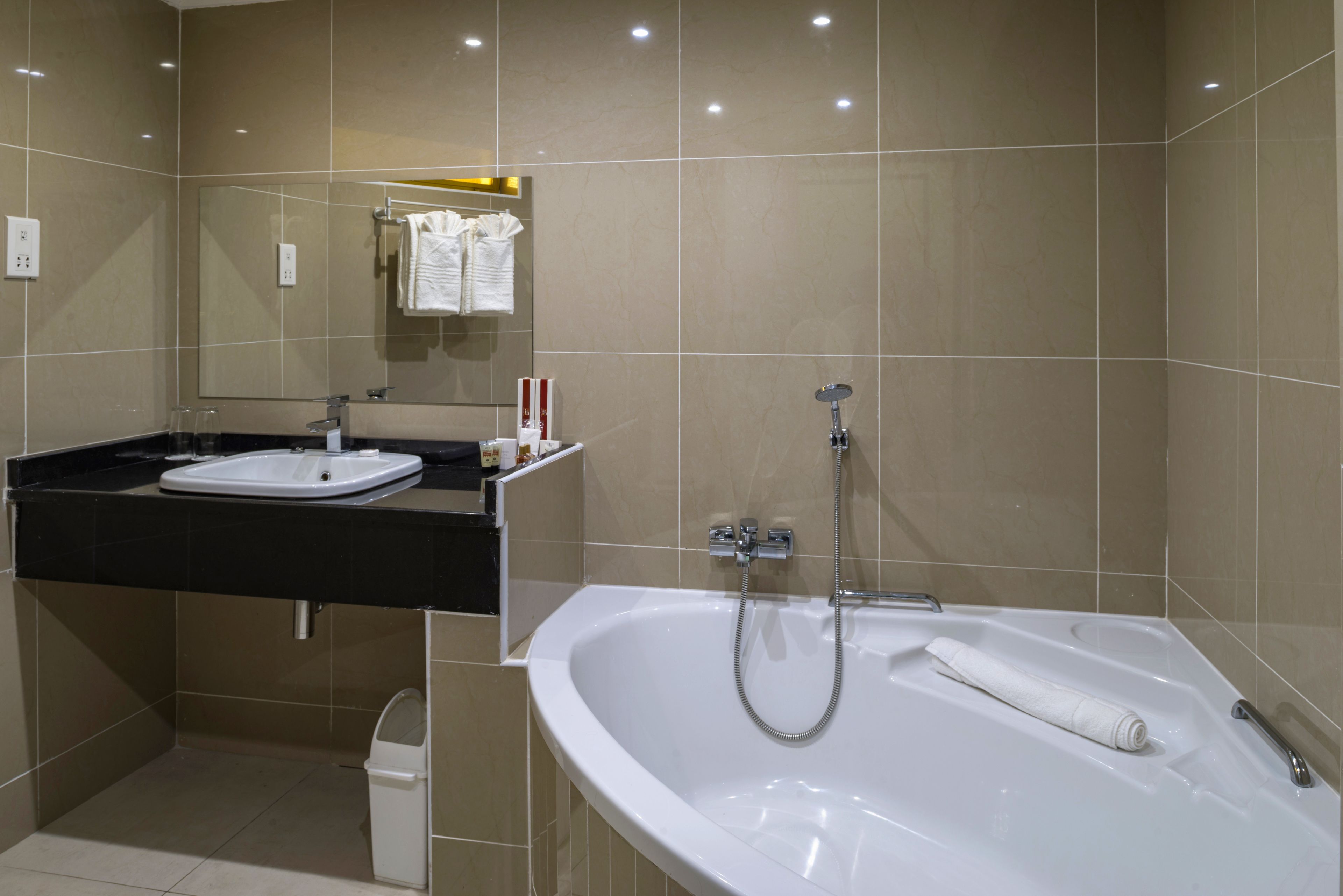 A modern bathroom with a white bathtub, a sink, and a mirror.