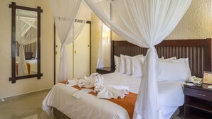 Una habitación de hotel con una cama grande, una mesita de noche, un espejo y dosel.