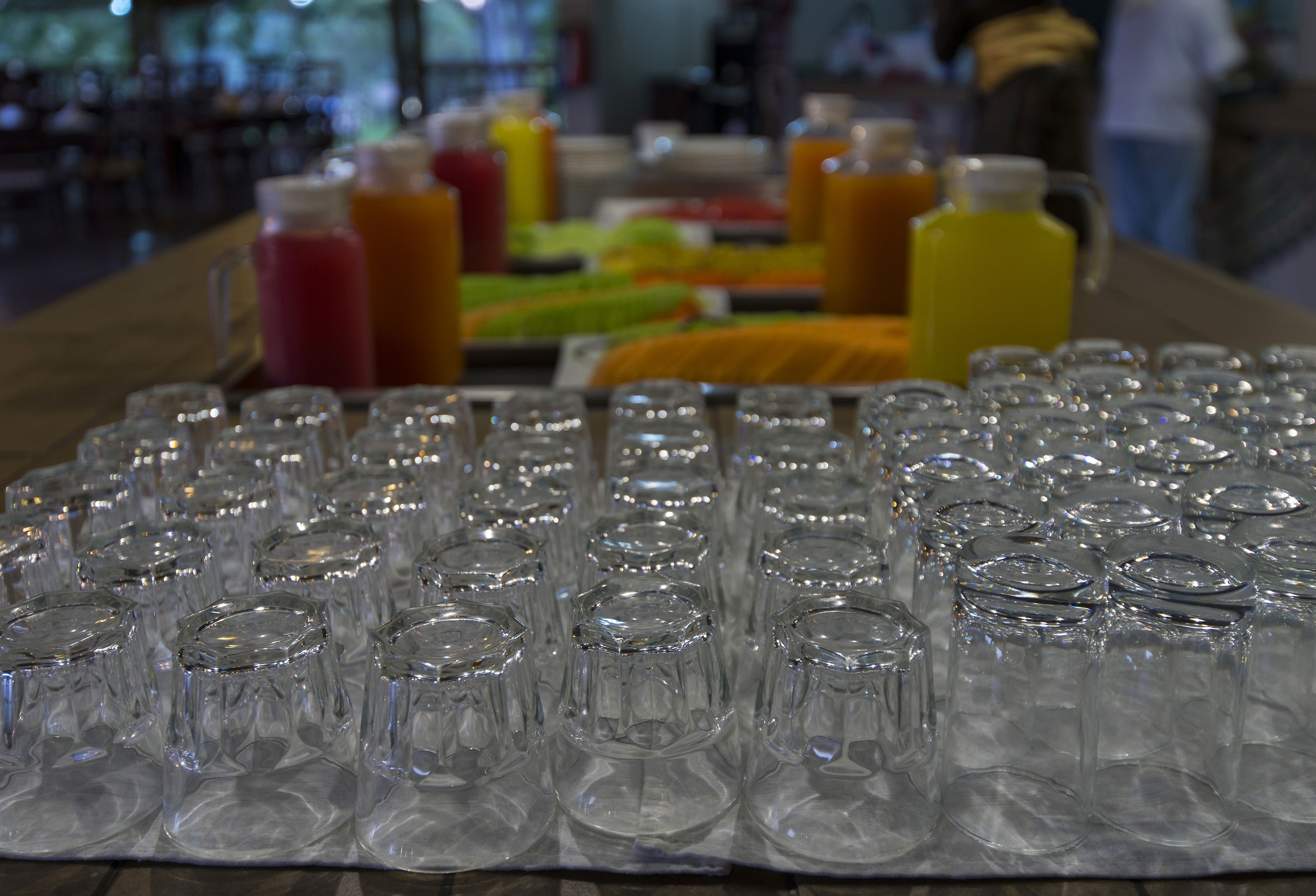 Une table avec plusieurs verres vides et diverses boissons en arrière-plan.