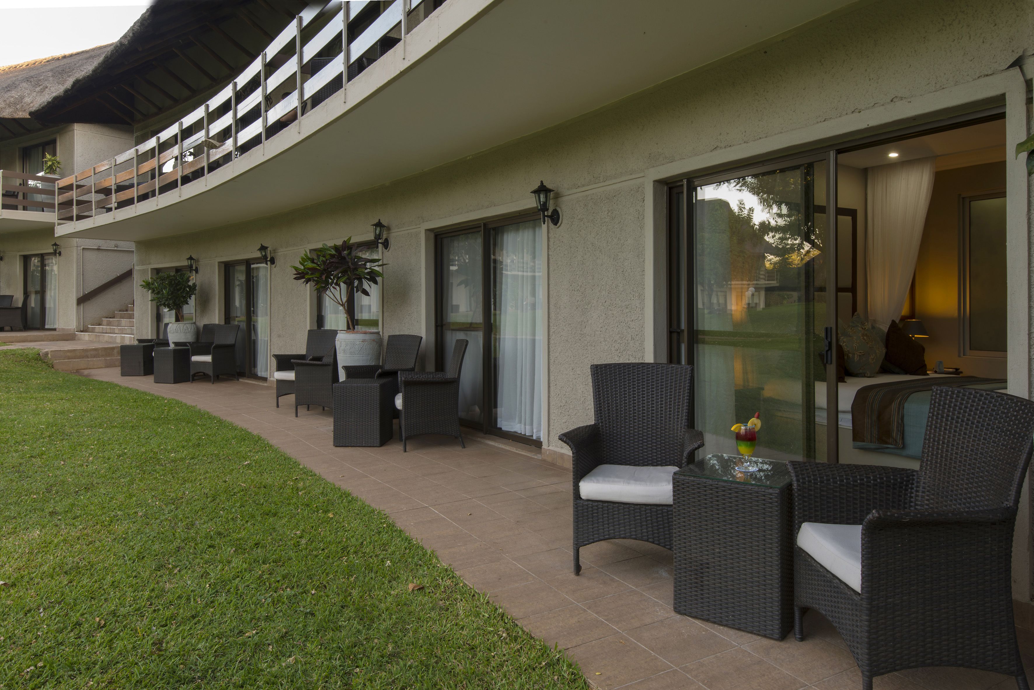 Un patio moderno al aire libre con mobiliario de mimbre y puertas de vidrio que dan a una sala de estar.