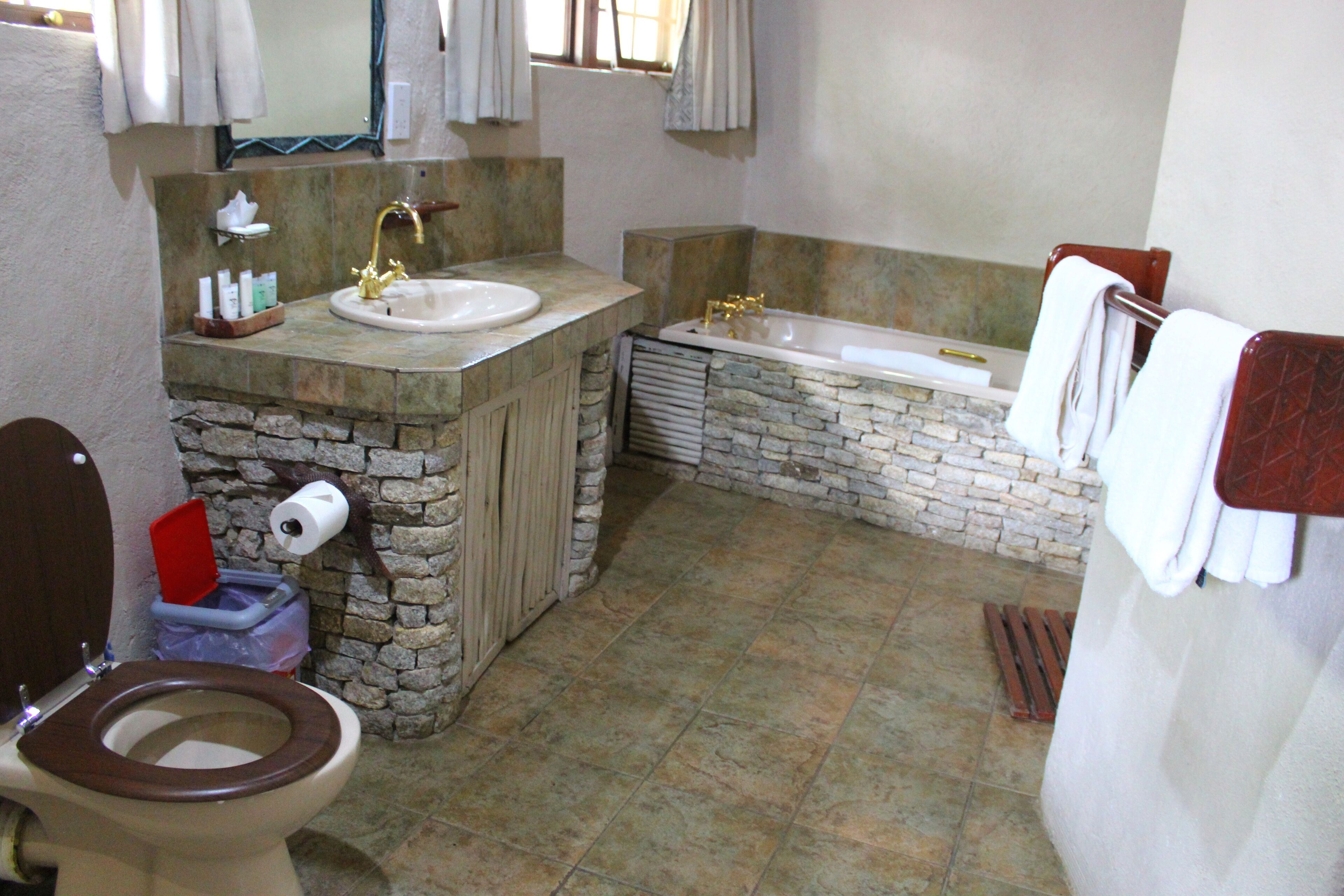 A bathroom with a stone sink, a bathtub, and a wooden toilet.