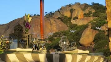Mesa al aire libre con vistas a colinas rocosas y vegetación.