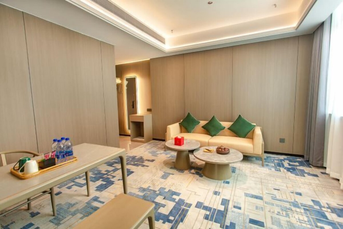 Habitació d'hotel moderna amb un sofà, una taula de cafè i una taula de menjador.