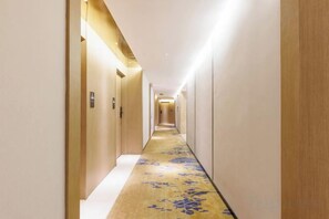 A hotel hallway with a carpeted floor, doors on both sides, and a light source at the end. - Foshan Sanshui ShiHuang Garden Hotel (Foshan)