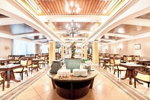 A spacious hotel dining area with multiple tables and chairs, a central round table with a vase, and a chandelier. - Foshan Sanshui ShiHuang Garden Hotel (Foshan)