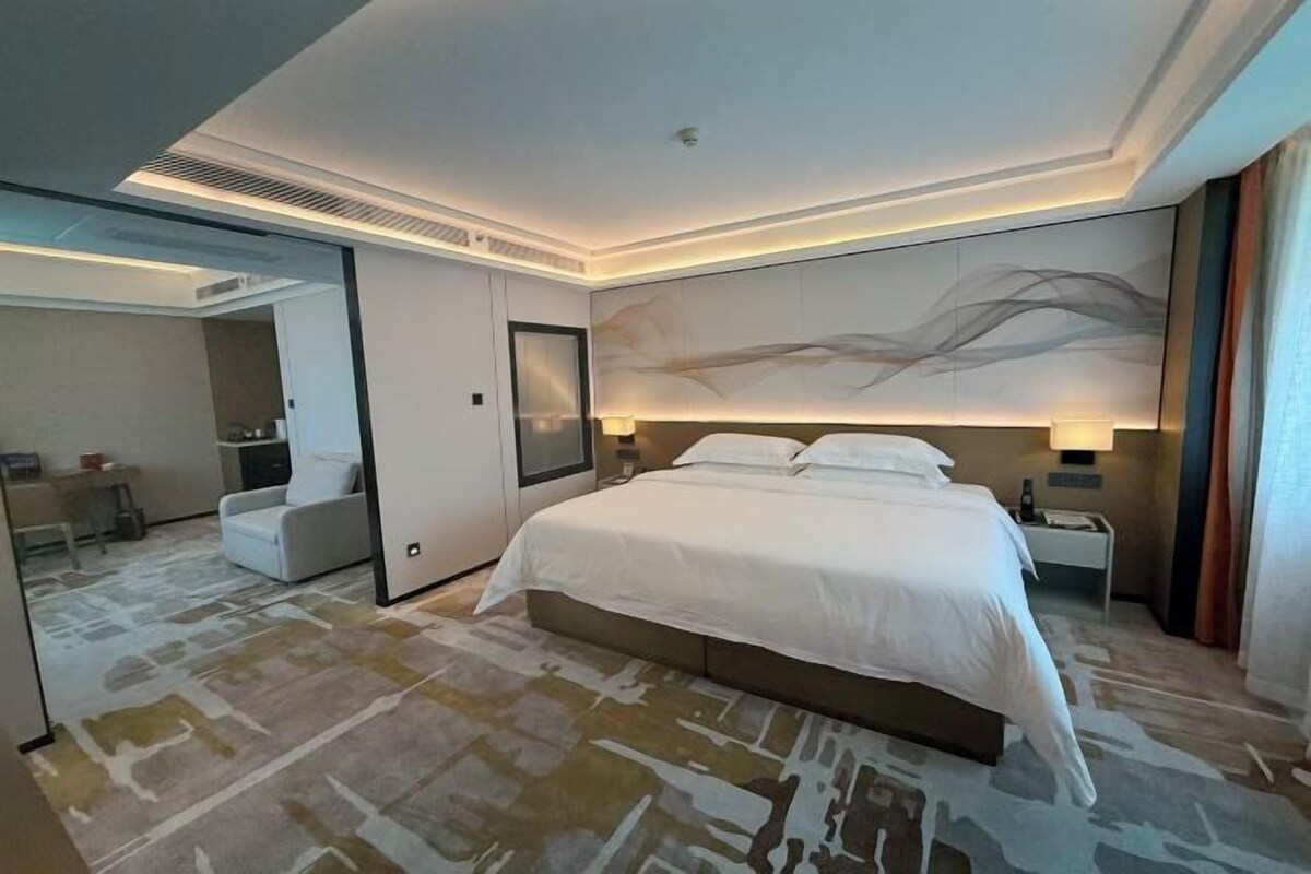 Una habitación de hotel moderna con una cama grande, un escritorio y un rincón de descanso.